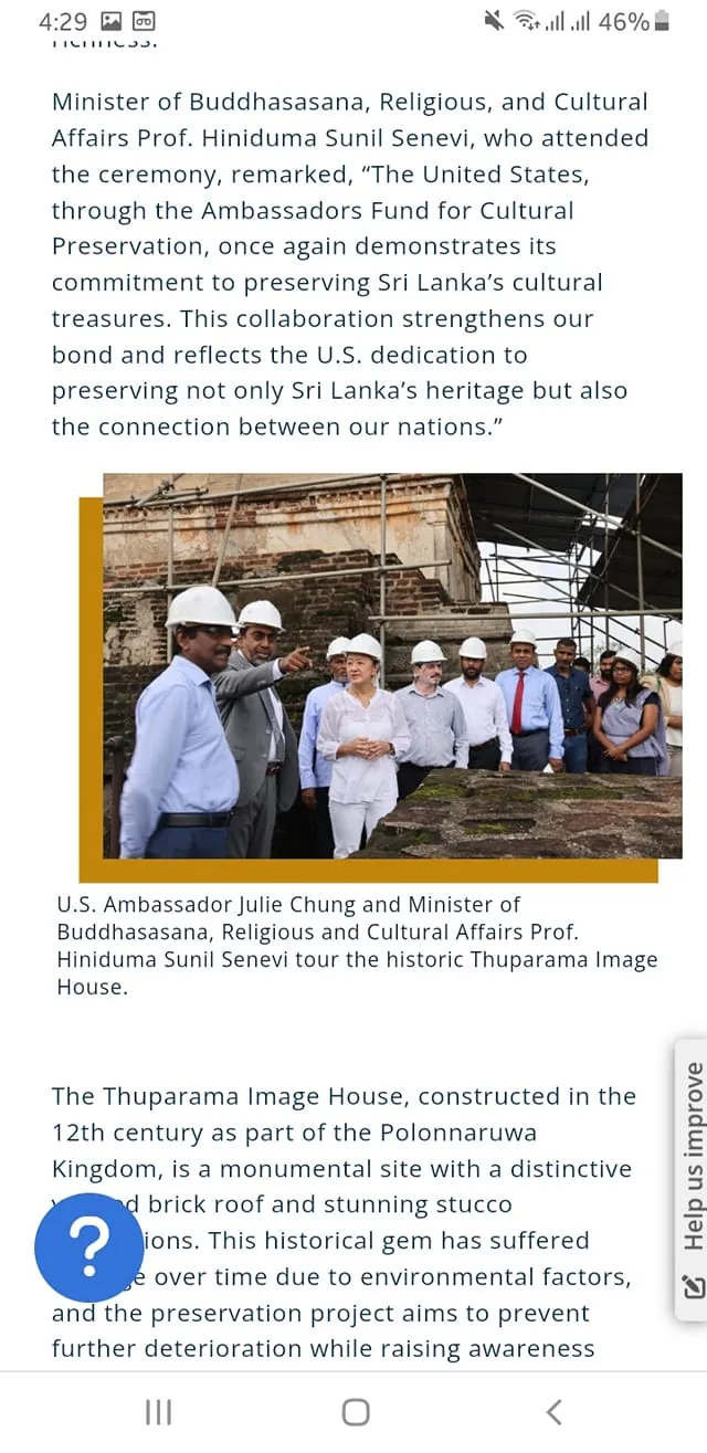 The image captures a significant moment during a tour of the historic Thuparama Image House, attended by U.S. Ambassador Julie Chung and Minister of Buddhasasana, Religious, and Cultural Affairs Prof. Hindiduma Sunil Senevi. Both figures are engaged in conversation, with Senevi gesturing towards the structure, indicating a discussion about its preservation. They are surrounded by a group of individuals, all wearing hard hats, suggesting that the site is undergoing restoration work. The setting appears to be outdoors, with scaffolding visible in the background, indicating ongoing construction or preservation efforts.

The Thuparama Image House, constructed in the 12th century as part of the Polonnaruwa Kingdom, is noted for its distinctive brick roof and stucco decorations. The text highlights the importance of this site, which has suffered from environmental damage over time. The preservation project aims to prevent further deterioration while raising awareness of its cultural significance. The atmosphere is one of collaboration and commitment to heritage conservation, reflecting the bond between the U.S. and Sri Lanka in preserving cultural treasures.