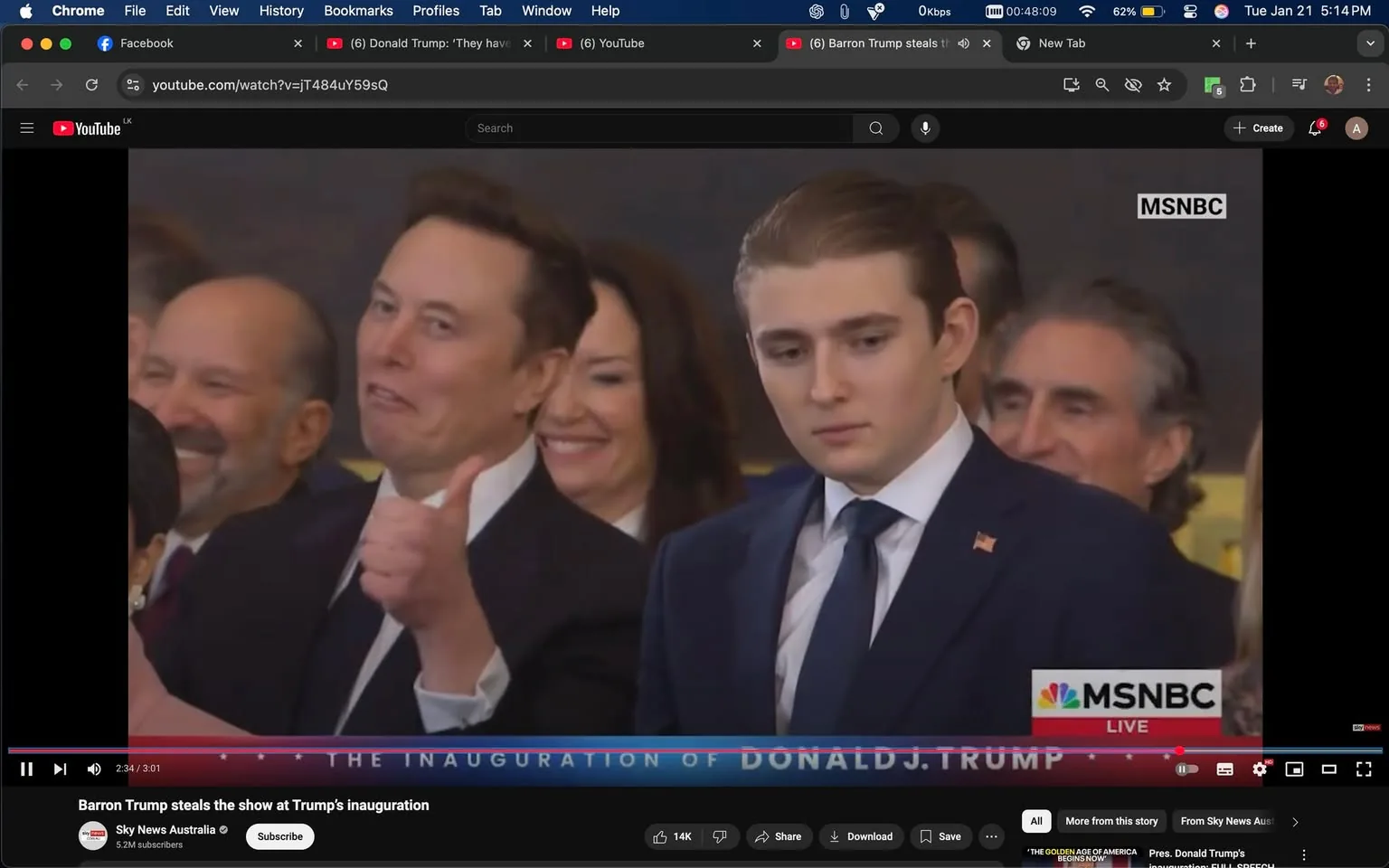 In the image, a group of individuals is gathered at what appears to be a formal event, likely an inauguration. The main focus is on a man on the left, who is making a thumbs-up gesture with a playful expression, suggesting a light-hearted moment. He is dressed in a dark suit and has short hair. Next to him is a young man with a serious expression, wearing a dark suit and a tie, indicating he is likely part of the same event. Behind them, there are several other individuals, including a woman with a smile, suggesting a mix of emotions among the attendees. The setting appears to be indoors, with a backdrop that hints at a significant political occasion. The overall atmosphere seems to be a blend of celebration and seriousness, typical of an inauguration event. There are no visible logos or brands in the image, and no sensitive content is present.