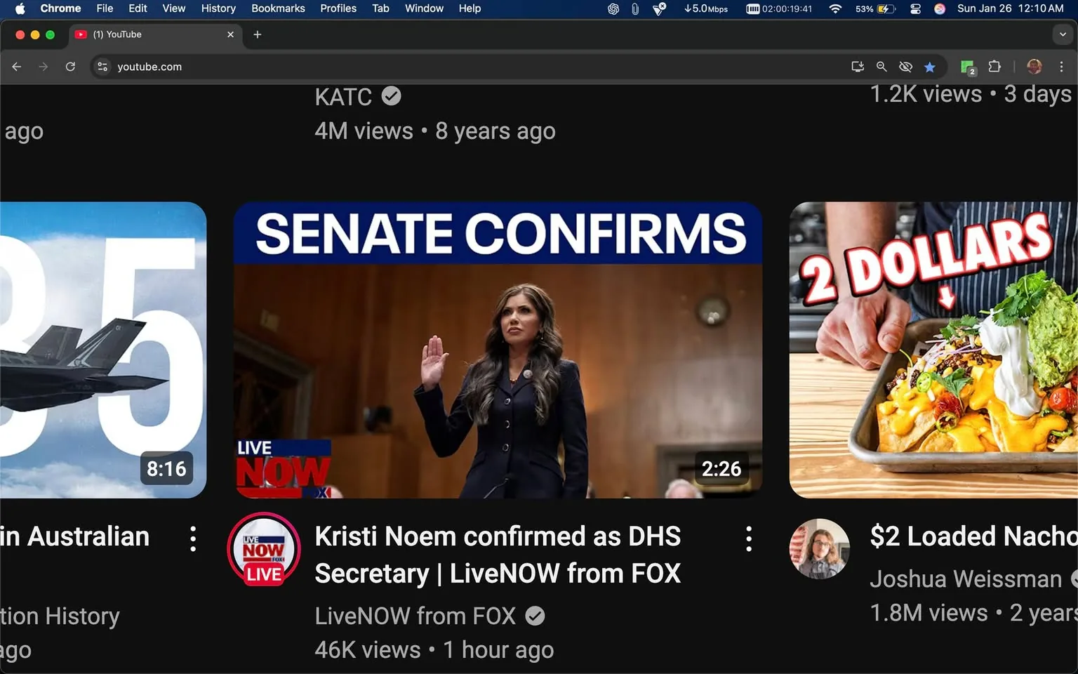 The image captures a YouTube interface displaying various video thumbnails. The main focus is on a video titled "Kristi Noem confirmed as DHS Secretary | LiveNOW from FOX," which features a woman raising her right hand, possibly taking an oath or making a statement. She has long, dark hair and is dressed in a dark suit, suggesting a formal setting, likely a Senate confirmation hearing. The background appears to be a wooden-paneled room, typical of governmental or official environments. 

Adjacent to this video is another thumbnail featuring a military aircraft with the number "35" prominently displayed, indicating it may relate to aviation or military topics. The third thumbnail showcases a cooking video titled "$2 Loaded Nachos," featuring a person holding a tray of nachos topped with various ingredients, emphasizing a budget-friendly meal. The interface indicates the view counts and upload times for each video, with the political video having 46K views and being uploaded an hour ago, while the military video has 4 million views from eight years ago. The overall layout is dark-themed, typical of YouTube's design, with clear, bold text for titles and view counts.