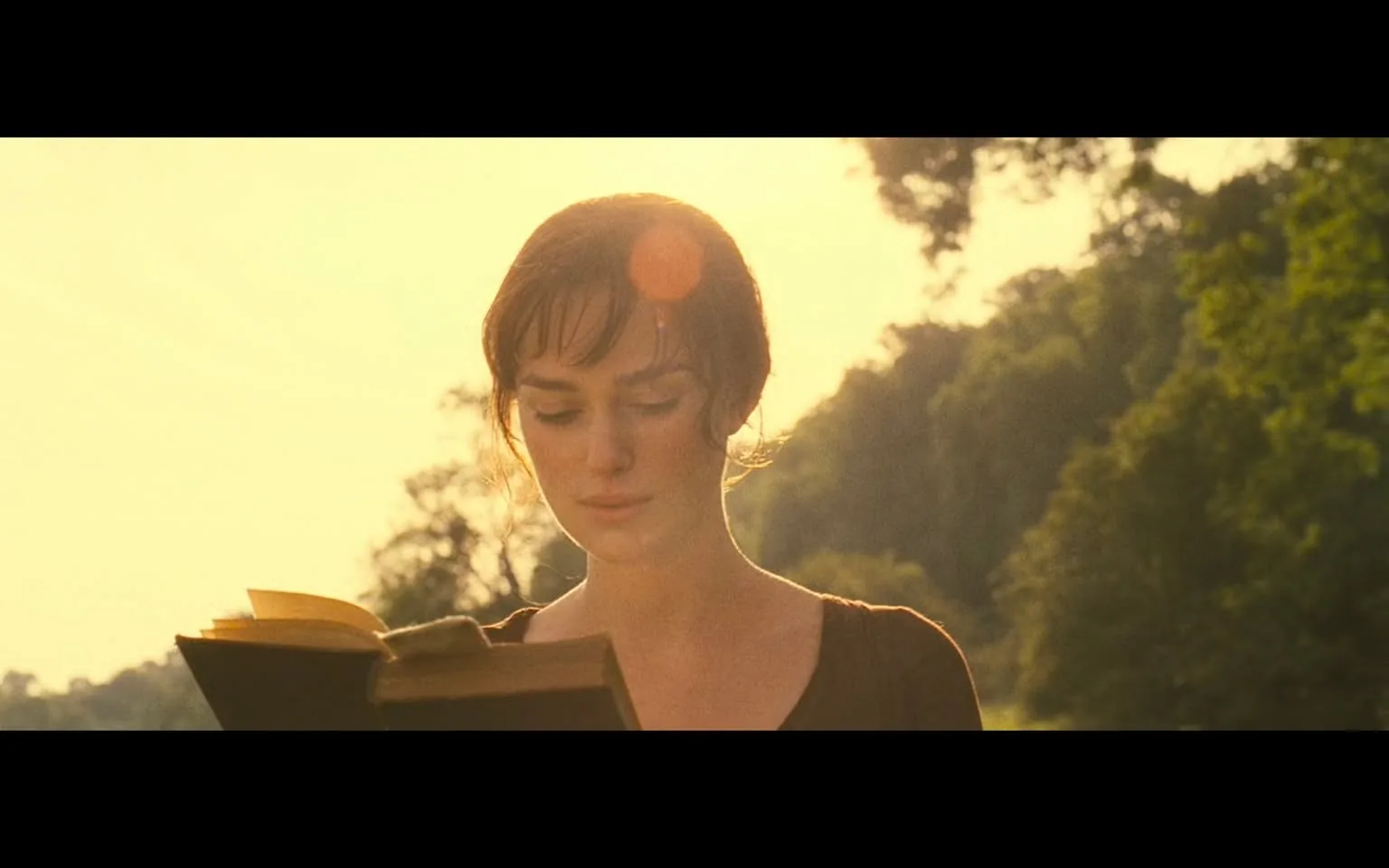 In this serene outdoor scene, a young woman stands bathed in the warm glow of a sunset, her expression contemplative as she reads a book. The sunlight filters through the trees behind her, creating a soft halo effect around her figure. The landscape is lush and green, suggesting a tranquil countryside setting. The woman, dressed in a simple brown dress, appears absorbed in her reading, with her hair slightly tousled by a gentle breeze. The book she holds is partially open, its pages catching the light, hinting at the story within. The overall atmosphere is peaceful and reflective, evoking a sense of calm and introspection. There are no visible signs of violence, sexual content, or any other concerning themes in this image, making it suitable for all audiences. The scene captures a moment of quiet solitude, inviting viewers to share in the beauty of nature and the joy of reading.