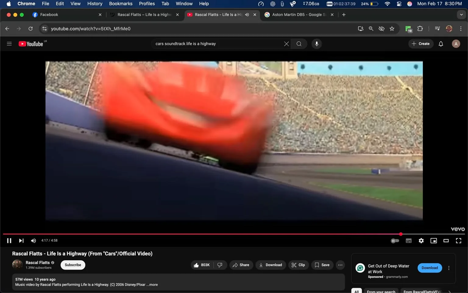 The image appears to be a still from a video featuring an animated scene, likely from the movie "Cars." In the foreground, a bright red car, resembling a race car, is depicted in motion, slightly blurred to indicate speed. The car has a distinctive design with a prominent front grille and large headlights. 

In the background, there is a large crowd in a stadium, suggesting a racing event. The stands are filled with numerous spectators, although individual faces are not discernible due to the distance and focus on the car. The setting appears to be a racetrack, with a smooth asphalt surface visible beneath the car. 

The video interface at the bottom shows that this is a music video for the song "Life Is a Highway" by Rascal Flatts, with the title and artist's name displayed prominently. The video is currently at 4 minutes and 17 seconds into a total length of 4 minutes and 58 seconds. Below the video, there are various interactive elements such as buttons for subscribing, sharing, and downloading, along with a view count of 57 million and a subscriber count of 1.39 million for the channel.

Overall, the image captures a dynamic moment in an animated racing context, emphasizing speed and excitement, with a vibrant color palette dominated by the red of the car against the muted tones of the crowd and stadium.