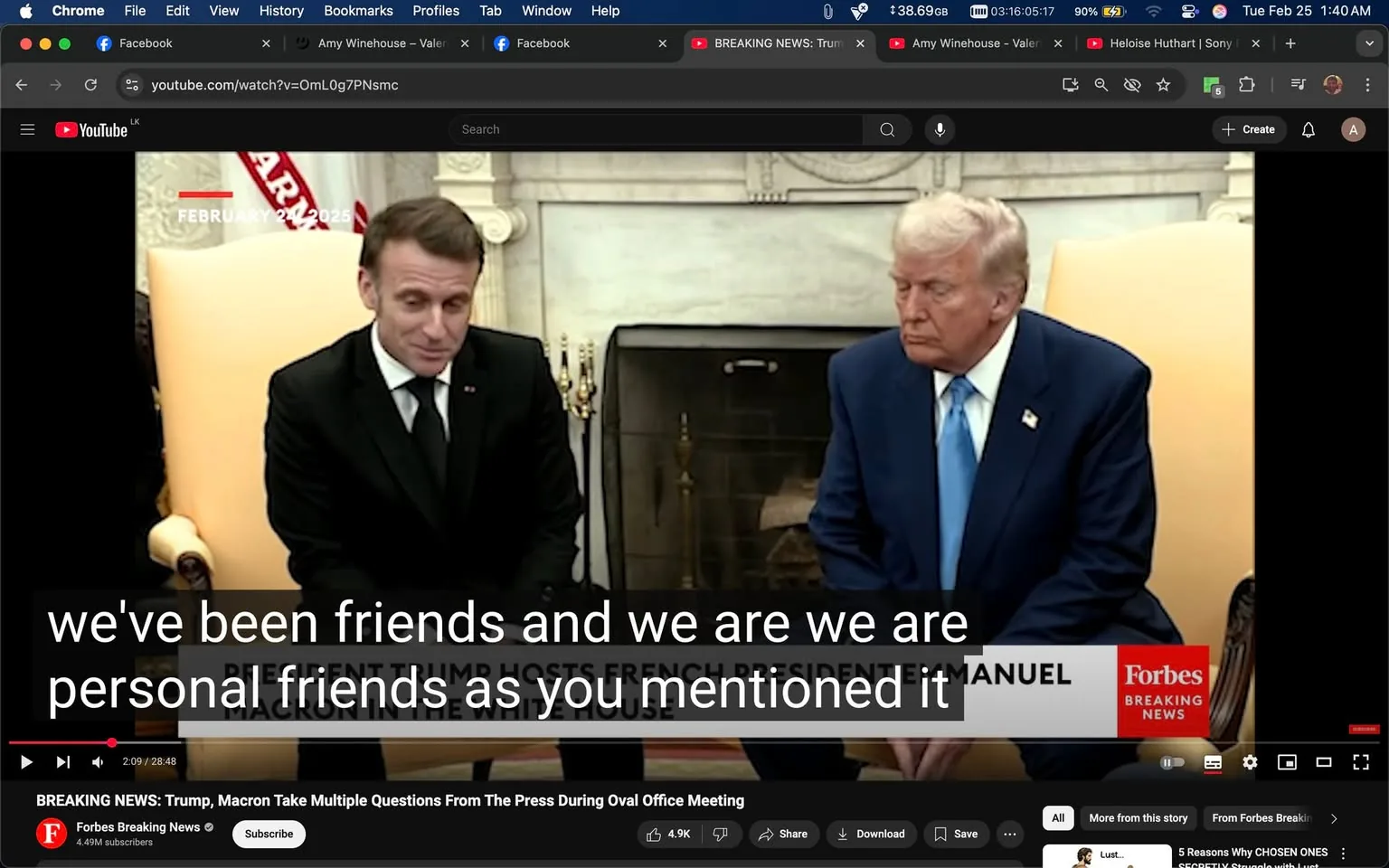 The image depicts a scene from a video conference or meeting taking place in an official setting, likely the Oval Office. 

**Readable Text:**
- There is a timestamp at the top left corner that reads "FEBRUARY 27, 2025."
- At the bottom of the image, there is a banner with the text "BREAKING NEWS: Trump, Macron Take Multiple Questions From The Press During Oval Office Meeting" and the logo of "Forbes Breaking News." The banner also includes a subscriber count of "4.9M subscribers."

**People:**
- On the left is a man dressed in a black suit with a white shirt and a black tie. He has short, dark hair and is slightly turned towards the right, appearing to speak or respond. His expression is neutral, with a slight smile.
- On the right is another man wearing a blue suit with a white shirt and a light blue tie. He has light-colored hair styled back and is looking downwards, appearing contemplative or serious. 

**Clothing and Appearance:**
- The man on the left (possibly Emmanuel Macron) is wearing a tailored black suit, which is complemented by a white dress shirt and a black tie. His hair is neatly styled.
- The man on the right (possibly Donald Trump) is dressed in a blue suit, with a white dress shirt and a light blue tie. His hair is light-colored and styled in a distinctive manner.

**Setting and Background:**
- The background features a light-colored wall with decorative elements, possibly a fireplace, which is visible behind the two men. There are gold accents and ornate details typical of an official government setting.
- To the left of the man in black, there is a light-colored armchair, and to the right, there appears to be a decorative item or furniture piece, possibly a table or another chair.

**Environmental Context:**
- The setting is formal, indicative of a high-level meeting or press conference. The presence of the banner suggests that this is a live broadcast or recording intended for public viewing.

Overall, the image captures a moment of interaction between two prominent figures in a formal governmental context, with specific visual details that highlight their attire and the setting.