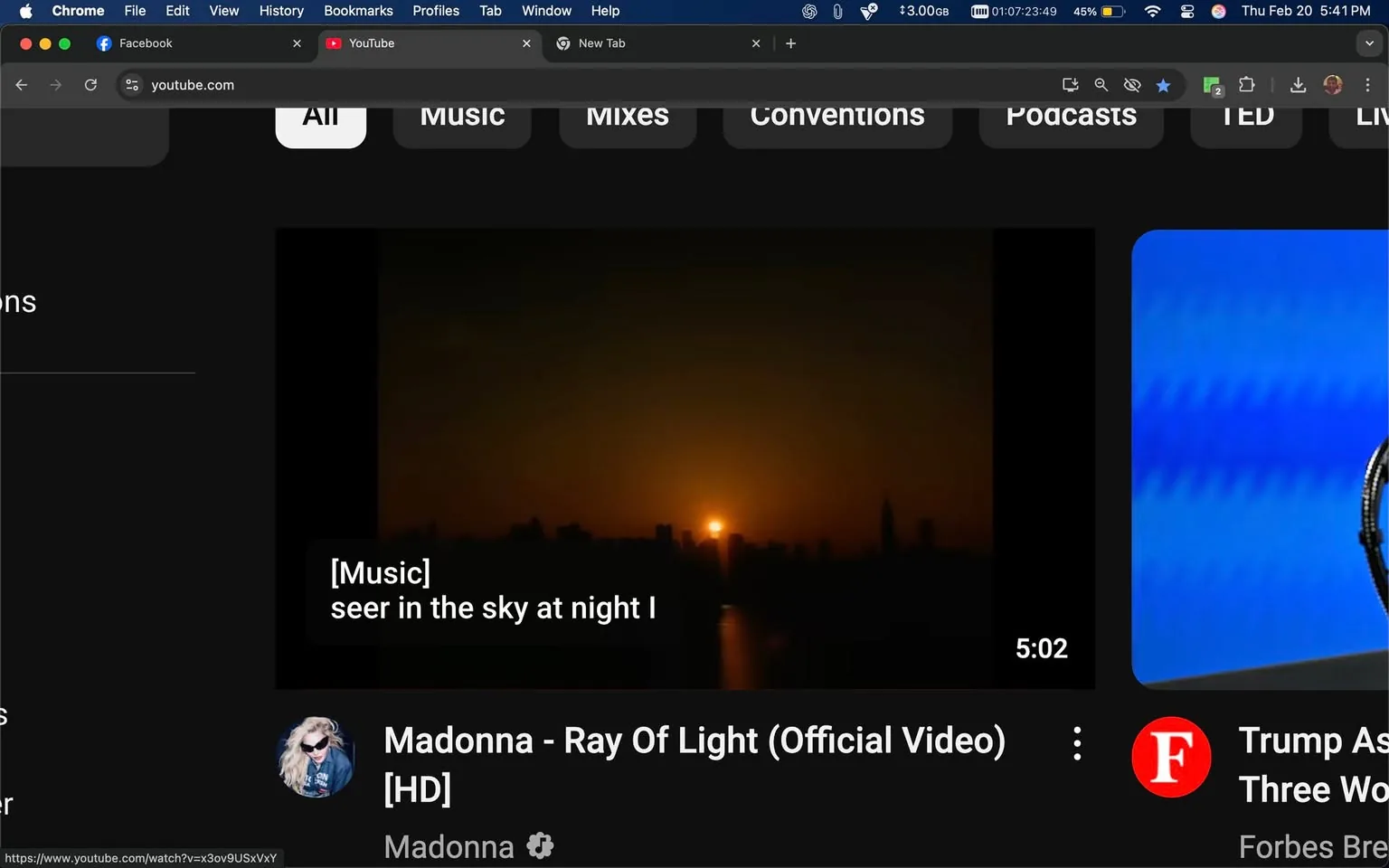 The image displays a screenshot of a web browser with two tabs open: Facebook and YouTube. The YouTube interface is prominently featured, showcasing a video player with a dark background typical of the platform's design.

1. **Readable Text**:
   - At the top of the YouTube interface, there are navigation tabs labeled "All," "Music," "Mixes," "Conventions," "Podcasts," "TED," and "LIVE."
   - In the video player, there is a subtitle displayed that reads: "[Music] seer in the sky at night I."
   - Below the video player, the title of the video is visible: "Madonna - Ray Of Light (Official Video) [HD]."
   - The name "Madonna" appears again, indicating the artist.

2. **Visible Brands and Logos**:
   - The YouTube logo is present in the top left corner of the video player.
   - The Facebook logo is visible in the browser tab, indicating that the other tab is for Facebook.

3. **Objects**:
   - The video player shows a sunset scene with the sun partially visible above a city skyline. The skyline includes silhouettes of buildings, but no specific architectural features are discernible.
   - The video duration is indicated as "5:02," suggesting the length of the video.

4. **Setting and Background**:
   - The background of the video player features a gradient of colors transitioning from dark to light, typical of a sunset, with the sun positioned near the horizon.
   - The overall setting appears to be a digital interface, specifically a video streaming platform.

5. **People**:
   - There are no visible people in the image. The focus is solely on the video content and the YouTube interface.

6. **Environmental Context**:
   - The screenshot captures a moment from a music video, indicated by the title and the presence of music-related text. The dark theme of the YouTube interface suggests a nighttime viewing experience.

Overall, the image is a digital representation of a YouTube video interface featuring a music video by Madonna, with a sunset scene as the visual content. The interface elements are consistent with standard web browser and video player designs.