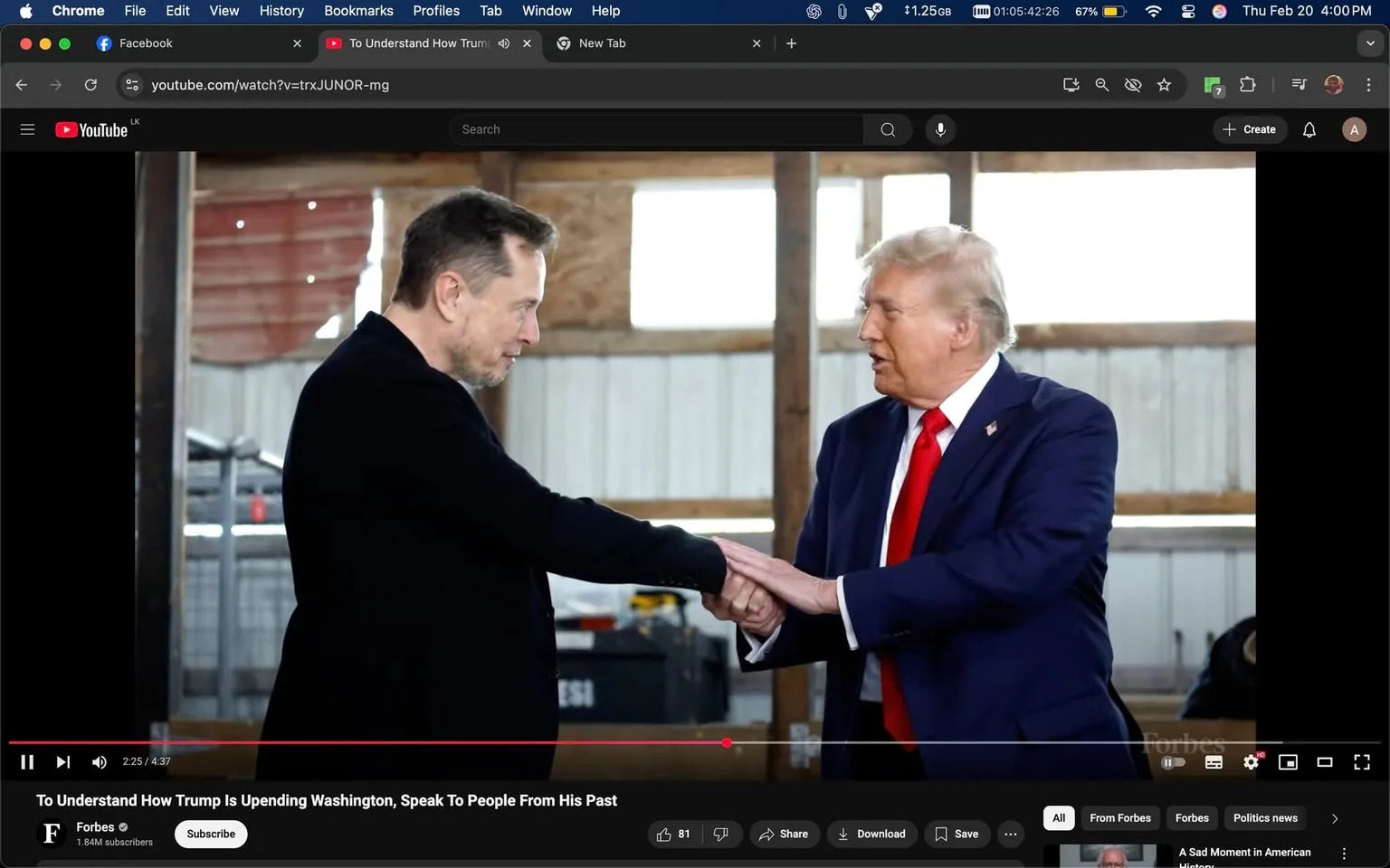 The image depicts two men engaged in a handshake. On the left, a man with short, dark hair and a light beard is wearing a black jacket over a dark shirt. He has a serious expression as he looks at the man on the right. The man on the right has light-colored hair styled back and is wearing a dark blue suit with a white shirt and a bright red tie. His expression appears focused as he looks back at the man on the left.

Both individuals are positioned in a well-lit indoor setting, which appears to be a barn or warehouse. The background features wooden beams and a corrugated metal wall, with some light filtering through windows. There are indistinct objects in the background, possibly equipment or storage items, but they are not clearly identifiable.

In the lower part of the image, there is a YouTube video player interface visible, showing a timestamp of 2:25 out of a total of 4:37. The video is titled "To Understand How Trump Is Upending Washington, Speak To People From His Past," and it is associated with the Forbes channel, which is indicated by a logo in the bottom left corner. The interface also displays options to like, share, and download the video.

No additional text, signs, or logos are visible in the image apart from the YouTube interface. The overall atmosphere of the setting is casual yet formal, given the attire of the individuals involved.