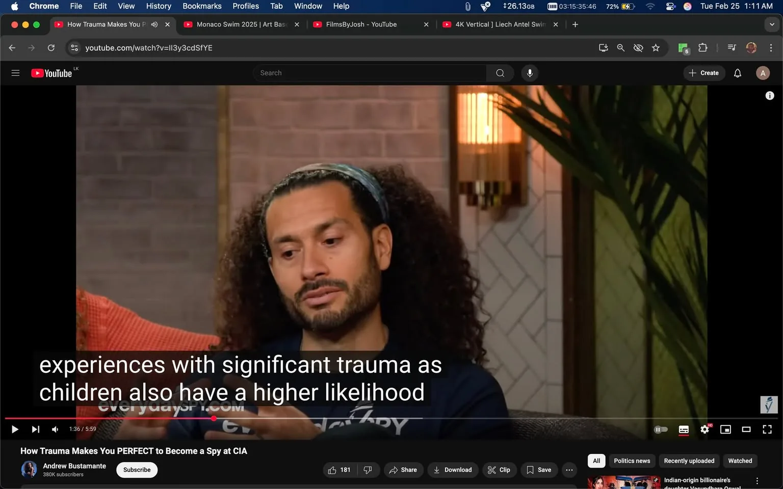 The image shows a scene from a YouTube video titled "How Trauma Makes You PERFECT to Become a Spy at CIA." The video features a man with curly hair, wearing a dark blue shirt with the word "Courage" printed on it. He has a headband that matches the color of his shirt, and he appears to be in a thoughtful pose, looking slightly downwards as he speaks. His facial expression suggests he is engaged in a serious discussion.

The background consists of a textured wall with a warm, neutral color, possibly beige or light brown. To the left of the man, there is a red-orange couch, and to the right, a green plant with long leaves is partially visible. A decorative wall sconce is mounted on the wall behind him, emitting a soft light, which adds to the warm ambiance of the setting. 

The video interface at the bottom shows a timestamp of 1:36 out of a total length of 5:59. There are subtitles displayed on the screen, which read: "experiences with significant trauma as children also have a higher likelihood." The YouTube logo is visible in the top left corner, along with options for subscribing and other video controls.

The overall setting appears to be a casual yet professional environment, likely designed for an interview or discussion format. The lighting is soft, contributing to a relaxed atmosphere. The video is being viewed on a computer screen, as indicated by the visible browser window at the top, which includes tabs for other videos and a search bar.