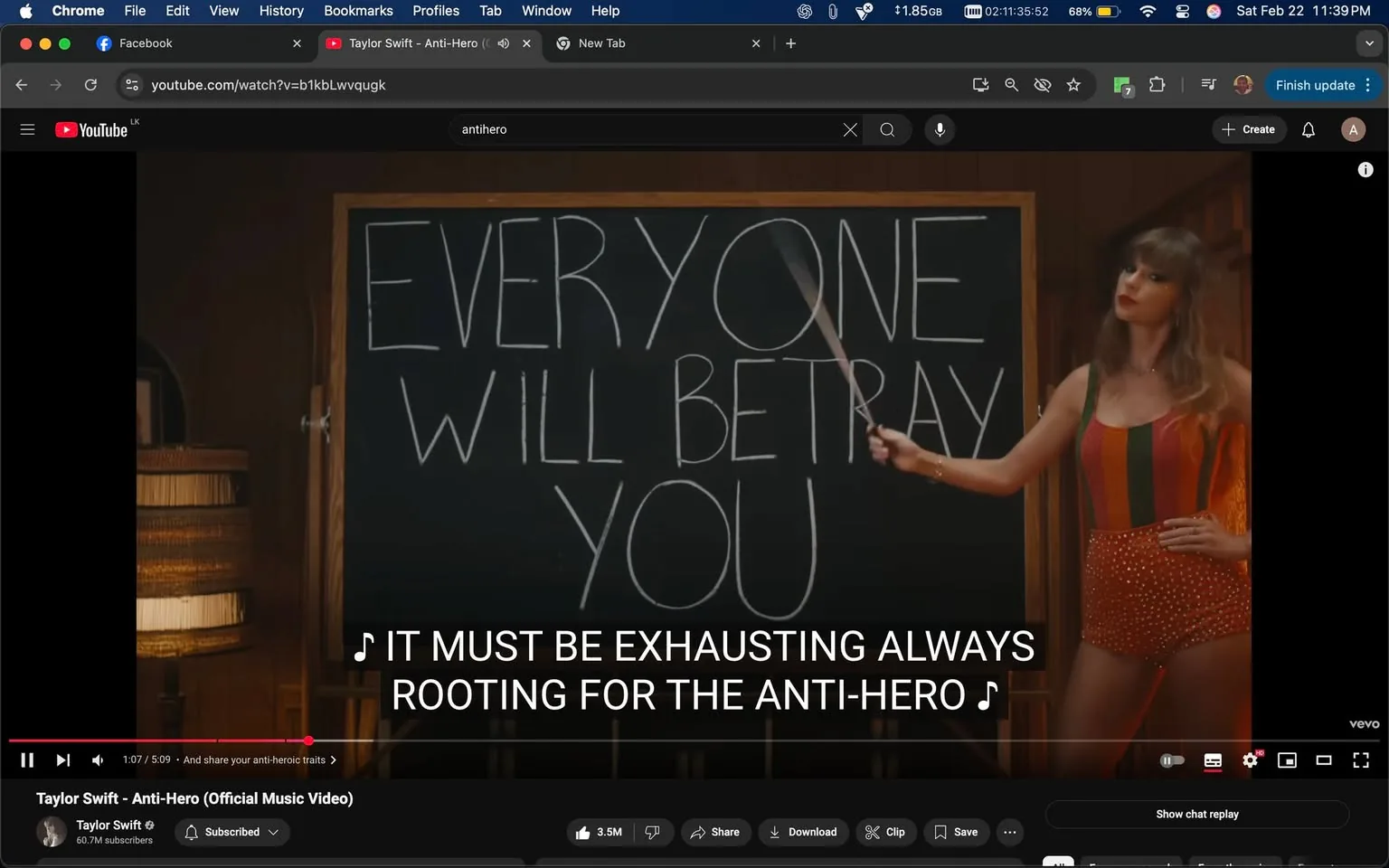 The image features a scene from a music video. In the foreground, a woman stands next to a large chalkboard. The chalkboard displays the text "EVERYONE WILL BETRAY YOU" written in large, white letters. The woman is holding a pointer stick and appears to be gesturing towards the chalkboard. 

She is dressed in a colorful, striped outfit that has a retro aesthetic, with shades of red, green, and yellow. The outfit is sleeveless and fitted, accentuating her figure. Her hair is styled in loose waves, and she has a confident expression on her face, with a slight smile and red lipstick.

The background consists of wooden paneling, giving the setting a warm, rustic feel. There is a wooden chair visible to the left, and a lamp with a woven shade is partially visible, suggesting a cozy indoor environment. The lighting is soft, contributing to the overall warm ambiance of the scene.

At the bottom of the image, there are subtitles that read, "IT MUST BE EXHAUSTING ALWAYS ROOTING FOR THE ANTI-HERO," indicating that this is a music video for a song titled "Anti-Hero." The video is hosted on YouTube, as indicated by the interface visible at the top of the image, which includes the YouTube logo and playback controls.

Overall, the image captures a moment of performance, with a focus on the woman and the message on the chalkboard, set in a visually appealing and thematic environment.