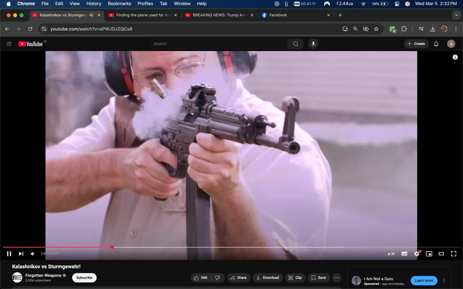 The image depicts a man firing a firearm, specifically an automatic weapon, in a shooting range environment. 

**Observable Details:**

- **Person:** The individual appears to be a middle-aged man with glasses. He has short, dark hair and is wearing protective ear muffs, which are black and red. He is dressed in a light-colored, short-sleeved shirt that is slightly unbuttoned at the collar, revealing a white undershirt. His left arm is extended forward, gripping the firearm, while his right hand is positioned on the weapon's grip.

- **Firearm:** The weapon being fired is a compact automatic rifle, possibly resembling a variant of the Kalashnikov design. It has a black finish and features a vertical grip, a rail system on the top for attachments, and a magazine inserted into the bottom. Smoke is visibly emanating from the muzzle, indicating that a shot has just been fired. A spent cartridge is seen ejecting from the firearm, adding to the dynamic action of the moment.

- **Setting:** The background is somewhat blurred, suggesting a shooting range or outdoor area designed for firearms practice. There are hints of a structure or wall behind the shooter, but specific details are not discernible due to the focus on the action.

- **Action:** The man is in the process of shooting, with his body slightly leaned forward, indicating engagement with the target. His facial expression is concentrated, focusing on aiming the firearm.

- **Text and Logos:** The video player interface is visible at the bottom of the image, showing the YouTube logo and controls for play, pause, and volume. The title of the video, "Kalashnikov vs Sturmgewehr!" is displayed prominently, along with the channel name "Forgotten Weapons" and a subscriber count of 2.9 million. There are also social media icons and options to share or download the video.

Overall, the image captures a moment of action in a controlled shooting environment, highlighting the equipment and safety measures typically associated with firearms practice.