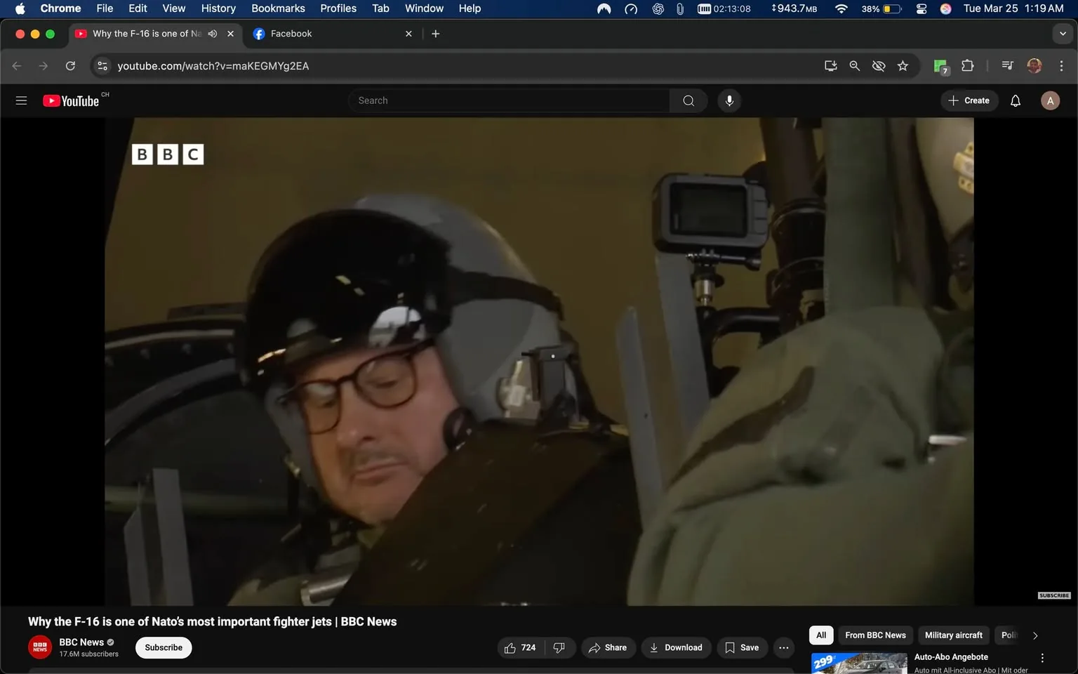 The image shows a man seated in what appears to be a cockpit or a similar environment, likely related to aviation. He is wearing a dark helmet with a visor, which reflects light, and has a grayish flight suit. The man has short, dark hair and is wearing glasses. His expression seems focused as he looks down, possibly at controls or instruments in front of him.

To his right, there is a greenish flight suit or jacket draped over a seat or surface, suggesting a military or aviation context. The background is somewhat blurred but indicates an indoor setting, likely a hangar or a similar facility, with soft lighting that creates a warm atmosphere.

In the upper left corner, there is a logo that reads "BBC," indicating that this image is part of a video or content produced by the BBC. The video title, visible at the bottom of the image, reads: "Why the F-16 is one of NATO's most important fighter jets | BBC News." Below this title, there are various interactive buttons for engagement, such as "Subscribe," "Share," and "Download," along with a view count of 724.

There is also a small camera or recording device mounted on a pole in the background, suggesting that this scene may be part of a documentary or news segment. The overall setting conveys a sense of preparation or briefing related to aviation, specifically focusing on the F-16 fighter jet.
