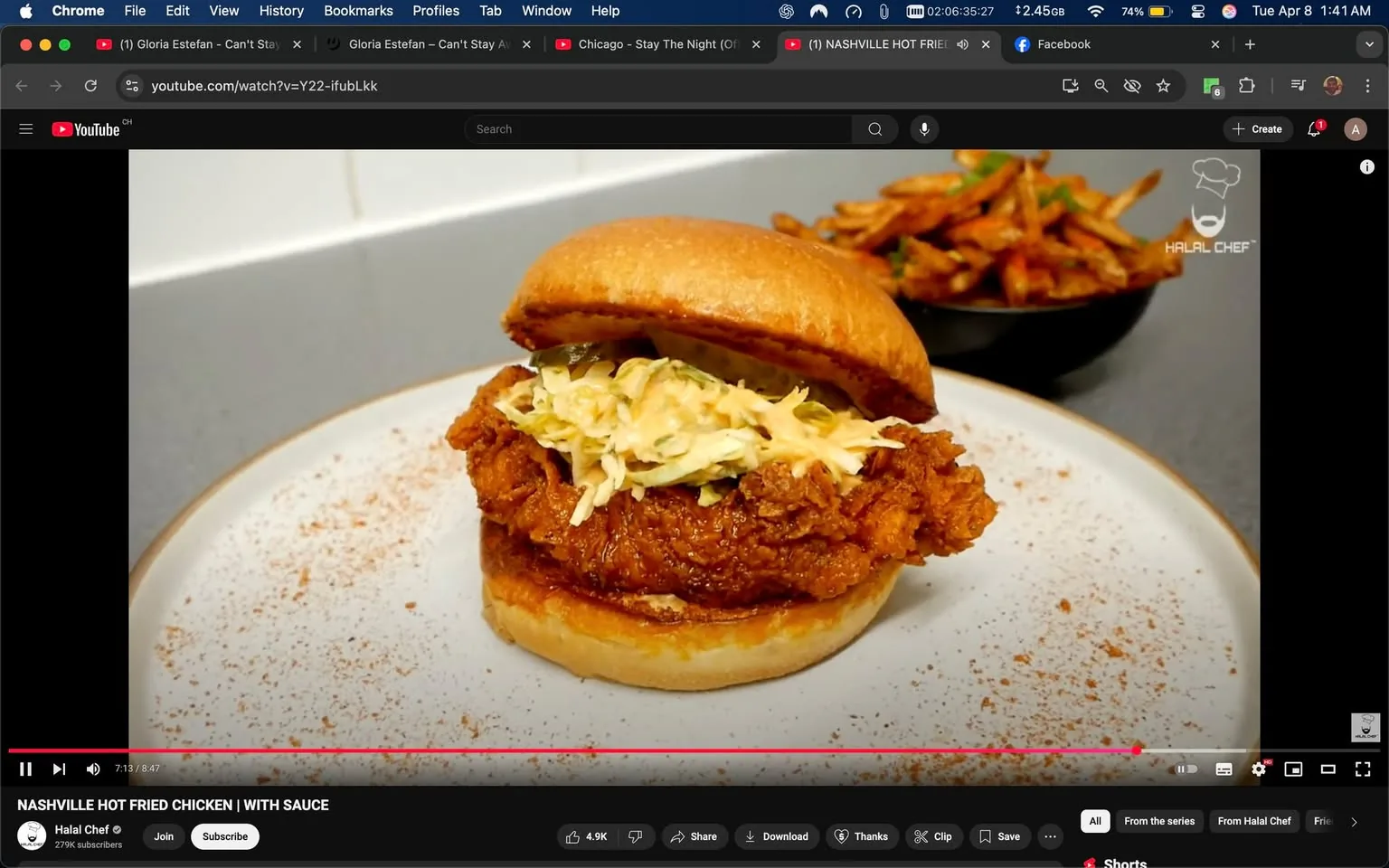 The image features a close-up view of a Nashville hot fried chicken sandwich placed on a round, white plate. The sandwich consists of a golden-brown, crispy fried chicken fillet that is visibly thick and has a textured surface, indicating a crunchy coating. On top of the chicken, there is a layer of shredded cabbage, which appears to be lightly dressed, adding a fresh contrast to the fried element. The sandwich is assembled with a soft, toasted bun that has a slightly shiny surface, and the bottom bun is visible, showing a bit of sauce that has soaked into it.

Surrounding the sandwich, there is a light dusting of what appears to be spices or seasoning, adding a visual appeal to the presentation. In the background, there is a bowl containing what looks like sweet potato fries, which are golden and crispy, with some green herbs sprinkled on top for garnish. The setting appears to be a kitchen or dining area, with a clean, modern countertop visible in the background, suggesting a casual dining environment.

The video interface at the bottom indicates that this is a YouTube video titled "NASHVILLE HOT FRIED CHICKEN | WITH SAUCE" from a channel named "Halal Chef," which has 279k subscribers. The video is currently playing, and the timestamp shows it is at 7 minutes and 13 seconds out of a total of 8 minutes and 47 seconds. There are options for sharing, downloading, and other interactive features visible in the video player interface. 

Overall, the image captures a well-presented food item, emphasizing the textures and colors of the ingredients, set against a simple and clean background.