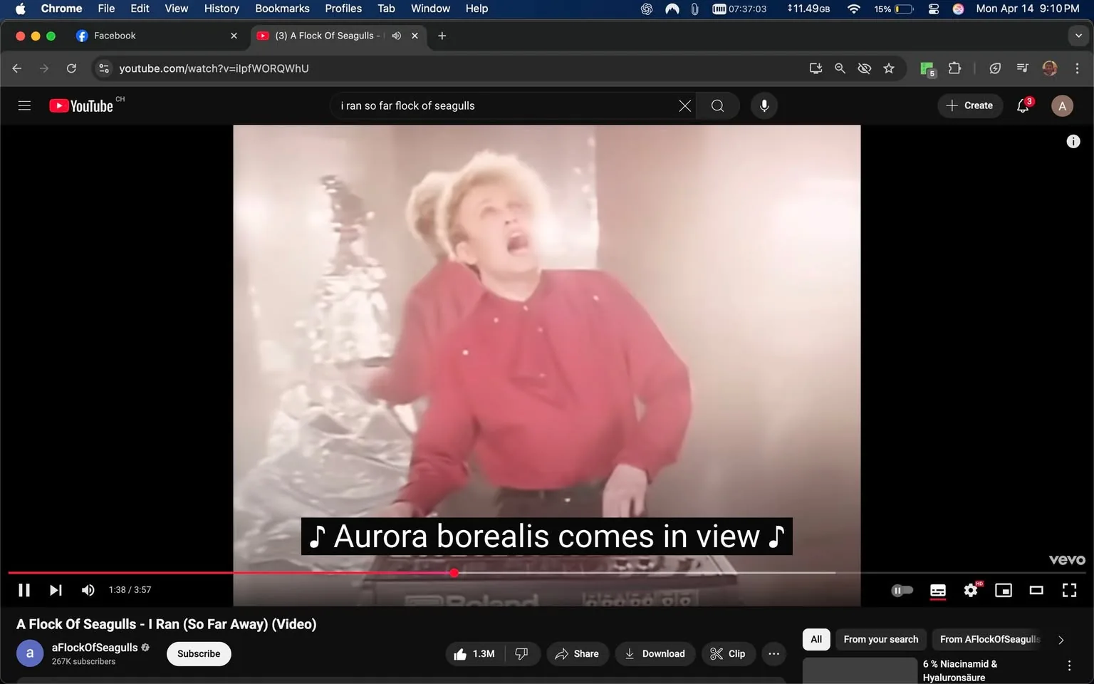 The image displays a scene from a music video titled "I Ran (So Far Away)" by the band A Flock of Seagulls. The video is playing on a YouTube interface, which is visible at the top of the image. The video is currently at 1 minute and 38 seconds into its runtime, with a total length of 3 minutes and 57 seconds. Below the video, there are several interactive elements, including a play/pause button, a timeline slider, and options to like, share, download, or clip the video. The channel name "aFlockOfSeagulls" is displayed, along with a subscriber count of 267K.

In the foreground, a male performer is prominently featured. He has a distinctive hairstyle that is voluminous and styled upwards, with light blonde or platinum color. He is wearing a bright red shirt that has a high collar and appears to be made of a soft fabric. The shirt features small decorative elements, possibly studs or embellishments, on the shoulders. His facial expression is animated, suggesting he is engaged in a performance, and he appears to be singing or playing an instrument.

The performer is positioned in front of a keyboard, which has a visible brand logo, "Roland," on it. The background is somewhat hazy and illuminated with soft lighting, creating a dreamlike atmosphere. There is a metallic or reflective object in the background, possibly a sculpture or decoration, which adds to the visual complexity of the scene.

The lower part of the image includes subtitles that read, "Aurora borealis comes in view," indicating that this is part of the song's lyrics. The overall setting appears to be a stage or performance area, likely designed for a music video, with an emphasis on visual effects and lighting to enhance the performance. The color palette is warm and soft, contributing to the nostalgic aesthetic typical of music videos from the 1980s.