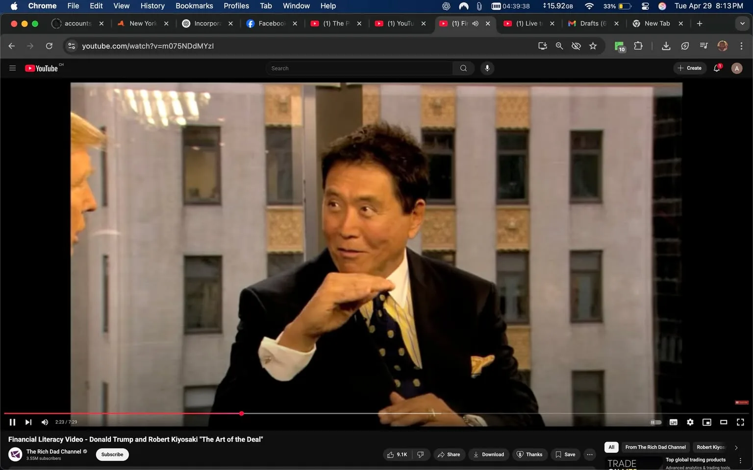 The image shows a scene from a video featuring two men engaged in conversation. The man on the left has light-colored hair styled in a comb-over and is wearing a dark suit with a white shirt and a red tie. His facial expression appears serious as he looks towards the other man. The man on the right has dark hair and is wearing a black suit with a white shirt and a yellow tie adorned with blue polka dots. He is gesturing with his right hand, holding it horizontally, possibly to emphasize a point in their discussion. His expression seems animated and engaged.

The background consists of large windows that reveal a view of a building's exterior, characterized by a beige facade with vertical lines and windows. The lighting in the room is bright, suggesting a daytime setting. There are reflections visible on the glass, indicating the presence of light sources, possibly overhead lights or sunlight.

The video interface at the bottom shows a play bar indicating the video is currently at 2 minutes and 23 seconds into a total length of 7 minutes and 29 seconds. The title of the video is "Financial Literacy Video - Donald Trump and Robert Kiyosaki 'The Art of the Deal'," and it is uploaded on "The Rich Dad Channel," which has 3.5 million subscribers. There are various icons for liking, sharing, and downloading the video, along with a comment section visible below the video player.

Overall, the scene captures a moment of dialogue between two individuals in a professional setting, with a focus on financial literacy.