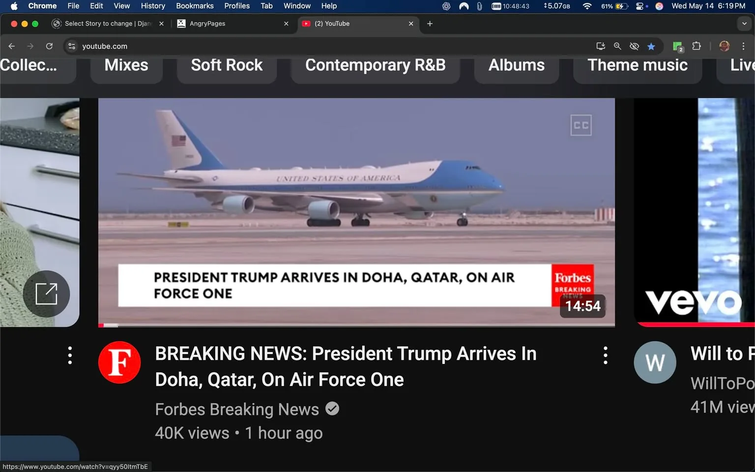 The image displays a video player interface from YouTube, featuring a news segment. The main visual element is an airplane, specifically Air Force One, which is a large aircraft painted predominantly in light blue and white. The aircraft has the words "UNITED STATES OF AMERICA" emblazoned on its side in capital letters. It appears to be on a runway, with a clear sky in the background, suggesting a location in Doha, Qatar.

At the bottom of the image, there is a white banner with the text "PRESIDENT TRUMP ARRIVES IN DOHA, QATAR, ON AIR FORCE ONE." This text is in a bold font, indicating the significance of the event being reported. The banner is branded with the logo of "Forbes Breaking News," which is displayed in red and white, indicating the source of the news.

To the left of the video player, there is a circular thumbnail image of a woman, possibly a content creator, who appears to be engaged in a conversation or presentation. She has long hair and is wearing a light-colored sweater, with a kitchen setting visible in the background, suggesting a casual or lifestyle context.

The bottom section of the image includes additional information about the video, stating "BREAKING NEWS: President Trump Arrives In Doha, Qatar, On Air Force One," along with the view count of "40K views" and a timestamp indicating it was posted "1 hour ago." The video duration is shown as "14:54."

The interface also includes various tabs at the top, labeled "Soft Rock," "Contemporary R&B," "Albums," and "Theme music," indicating a music-related context or options for the user. The overall layout is typical of a YouTube video player, with a dark background contrasting with the lighter elements of the video and text.