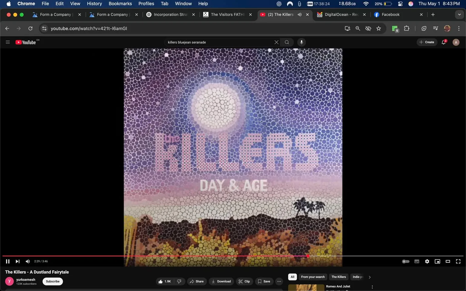 The image displays the album cover for "Day & Age" by the band The Killers. The cover features a mosaic-like design composed of numerous circular shapes in various colors, creating a visually striking pattern. 

At the top of the cover, the word "the" is written in a smaller font, followed by "KILLERS" in large, bold letters. The letters are rendered in a light pink color, which stands out against the background. Below "KILLERS," the text "DAY & AGE" is displayed in a slightly smaller font, also in light pink.

The background of the cover transitions from a deep purple at the top to a lighter pink towards the bottom. A large, circular shape resembling the moon is positioned in the upper center of the image, surrounded by smaller white dots that could represent stars. 

In the lower section of the cover, there is a silhouette of a desert landscape, featuring rolling hills and a few palm trees on the right side. The colors in this section are warmer, with yellows and browns dominating, suggesting a sunset or sunrise.

The overall composition is vibrant and colorful, with a blend of geometric shapes and natural elements, creating a unique artistic representation. The image is framed by a black border on the left side, while the right side remains blank. There are no visible people, clothing, or additional objects in the image. The setting appears to be purely artistic, with no specific environmental context beyond the depicted landscape.