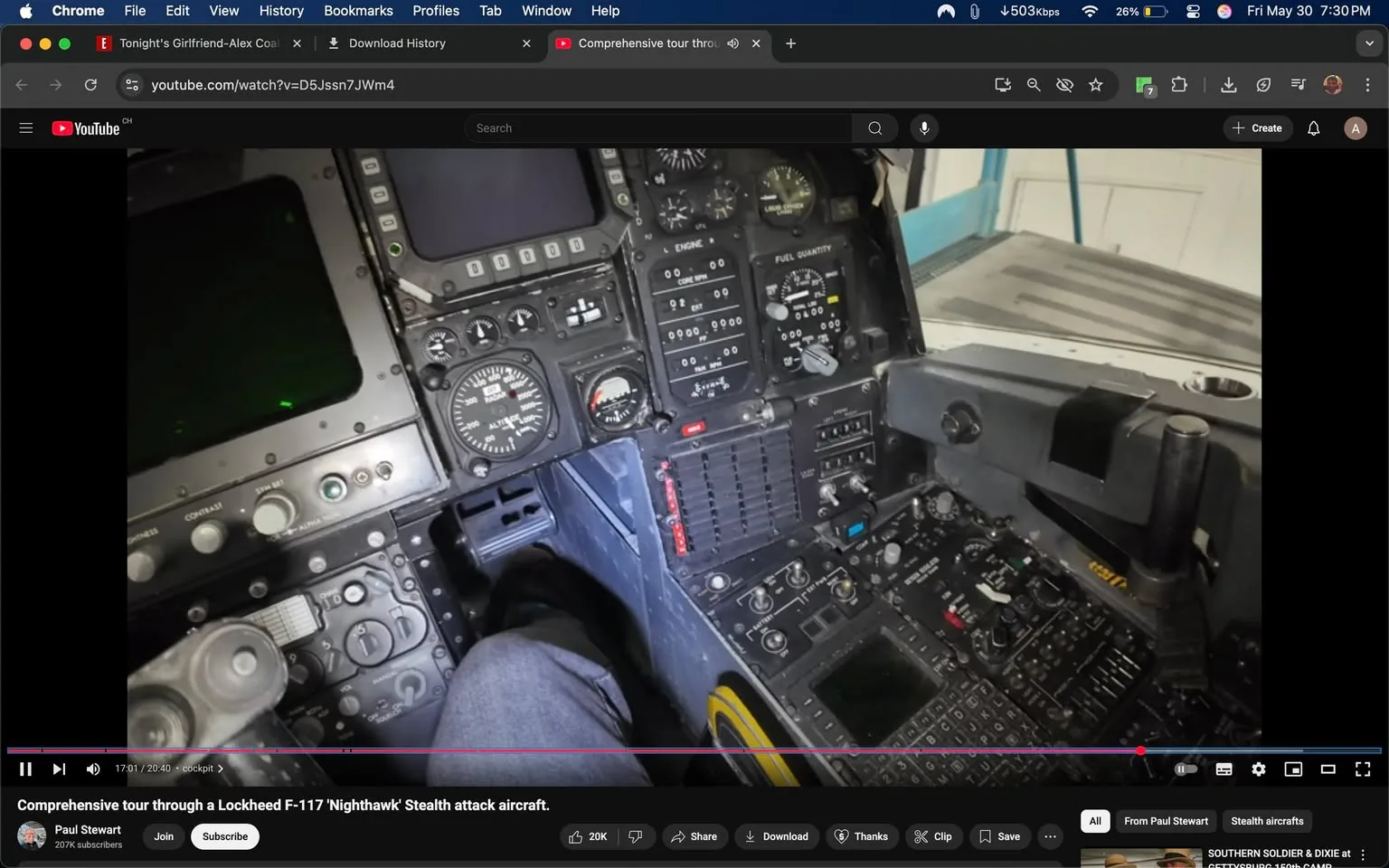 The image depicts the cockpit of a Lockheed F-117 Nighthawk stealth attack aircraft. The cockpit is filled with various instruments and controls, showcasing a complex array of dials, switches, and screens. 

**Instruments and Controls:**
- The left side features multiple analog gauges, including an altimeter and other flight instruments, with clear markings for altitude and speed.
- There are several digital displays, some of which are dark, indicating they may be turned off or inactive.
- A prominent control panel is visible, with numerous buttons and switches, many labeled with technical terms related to aircraft operation.
- A joystick or control stick is located on the right side, suggesting it is used for maneuvering the aircraft.

**Color and Material:**
- The cockpit is predominantly black, with metallic and plastic components. The surfaces appear to be matte, reducing glare.
- There are hints of green lighting, possibly from the instrument panels, contributing to a high-tech ambiance.

**Seating and Position:**
- A leg is visible, suggesting a seated position, possibly of a pilot or operator. The person appears to be wearing casual clothing, specifically dark pants.

**Background:**
- The background shows a light-colored wall, possibly part of a hangar or maintenance area, indicating the aircraft is likely stationary and being inspected or showcased.
- There is a hint of blue, possibly from equipment or tools in the background.

Overall, the cockpit is a highly specialized environment designed for advanced flight operations, reflecting the technological sophistication of military aircraft.