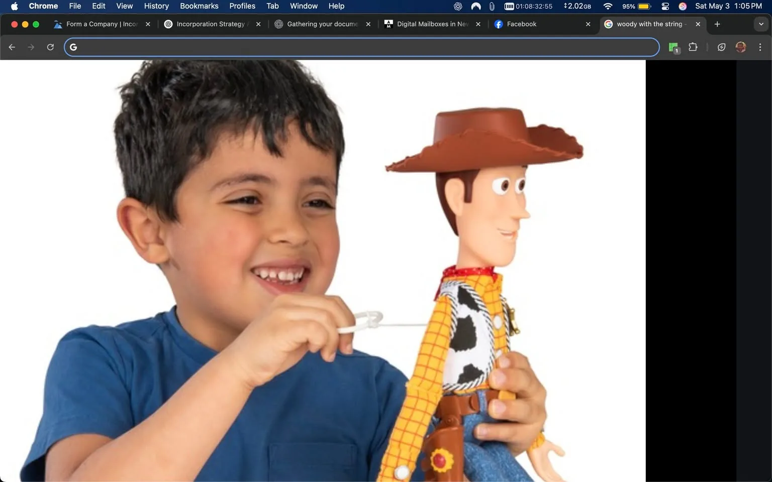 The image features a young boy, approximately 5 to 7 years old, with short, dark hair and a joyful expression. He is wearing a blue t-shirt. The boy is holding a toy figure resembling a cowboy character, which is likely inspired by a well-known animated film. The toy has a distinct cowboy hat, a yellow checkered shirt with a black and white cow print vest, blue jeans, and a brown belt with a holster. The character's face is animated, with large eyes and a friendly smile.

The boy appears to be interacting with the toy, using a small white string or pull mechanism that is attached to the figure. His facial expression conveys happiness and excitement, suggesting he is engaged in play. 

The background of the image is plain white, which emphasizes the subjects in the foreground. There are no visible logos, text, or additional objects in the background, creating a clean and focused visual. The overall setting appears to be indoors, likely in a home environment, given the simplicity of the background.

The toy character is a recognizable figure from popular culture, known for its association with themes of friendship and adventure. The boy's interaction with the toy suggests a playful and imaginative scenario, typical of children's playtime activities.