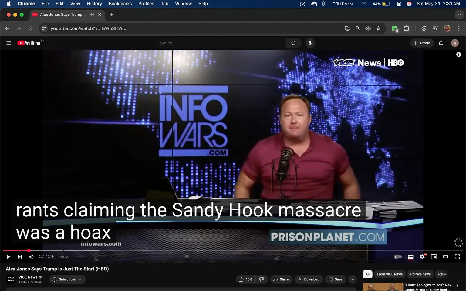 The image shows a video still from a YouTube broadcast featuring a man speaking into a microphone. He appears to be in a studio setting with a dark background illuminated by blue and white lights. The man is wearing a short-sleeved, maroon shirt and has a short, light-colored hairstyle. He is positioned at a desk with a microphone in front of him and appears to be gesturing with his hands as he speaks.

In the background, there is a large screen displaying the logo "INFOWARS.com" prominently in white text against a dark backdrop. The screen also features a digital map design with blue and white lights, suggesting a global theme. Below the logo, there is a website link that reads "prisonplanet.com."

The video includes subtitles at the bottom, which state, "rants claiming the Sandy Hook massacre was a hoax." The text is displayed in white against a black background, making it easily readable.

The overall setting appears to be a news or commentary studio, likely focused on controversial topics, given the content of the subtitles. The lighting is dramatic, with a focus on the speaker, enhancing the visual impact of the broadcast. The environment is professional, typical of a media production space.