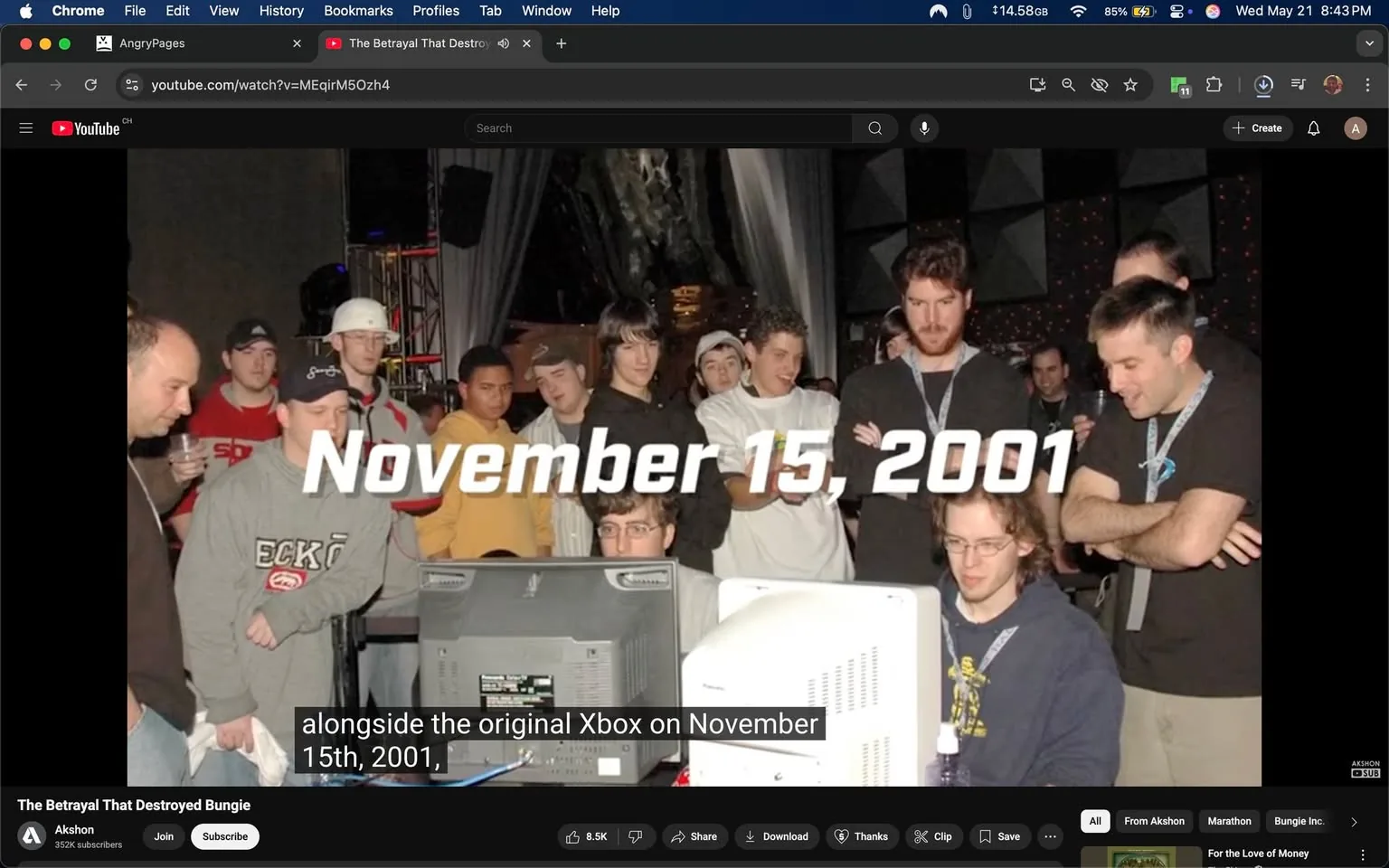 The image depicts a group of people gathered around two computer monitors, seemingly engaged in a gaming or tech-related event. The prominent text overlay reads "November 15, 2001," indicating a specific date, likely related to the event being showcased.

**Readable Text:**
- The date "November 15, 2001" is displayed in large, bold, white font across the center of the image.
- Below the date, there is a caption that reads "alongside the original Xbox on November 15th, 2001," which is partially obscured but visible.

**People:**
- There are several individuals in the image, primarily male, with a mix of casual clothing styles.
- The person in the foreground, seated at the computer, is wearing a dark hoodie and glasses. He appears focused on the screen.
- To his left, another individual is wearing a gray sweatshirt with the logo "ECKO" and is holding a drink. He has a slight smile.
- A third person, standing behind the seated individual, has dark hair and is wearing a black jacket. He has a serious expression.
- Several others are visible in the background, including individuals wearing baseball caps, a white hat, and a yellow sweatshirt. Their expressions range from curiosity to concentration as they watch the monitors.

**Clothing:**
- The clothing styles are casual, with hoodies, t-shirts, and jackets predominating. The colors vary, including gray, black, white, and yellow.
- Some individuals are wearing lanyards around their necks, suggesting they may be participants or attendees of an event.

**Setting:**
- The background features a dimly lit environment with a stage-like setup, indicated by draped fabric and possibly decorative lighting.
- There are additional people in the background, some appearing to be part of the event staff or other attendees.
- The monitors in front of the group are displaying content related to gaming, but the specifics are not visible.

**Objects:**
- The computers are desktop models, with one monitor being a CRT type, and the other appears to be a flat-screen.
- There are drinks and possibly snacks on the table, but specific details are not discernible.

Overall, the image captures a moment of engagement and excitement around a gaming event, likely related to the launch of the original Xbox, as indicated by the text and the presence of multiple individuals focused on the screens.