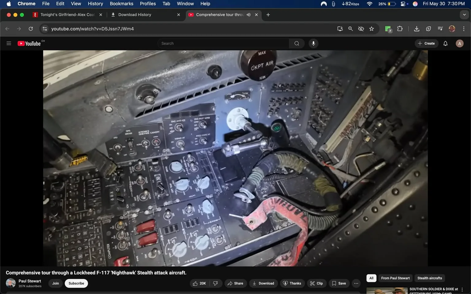 The image depicts the cockpit area of a Lockheed F-117 Nighthawk stealth attack aircraft. The cockpit features a complex array of controls and instruments, primarily in black and gray tones. 

1. **Control Panels**: The main control panel is visible, with various dials, switches, and buttons. There are several rotary knobs, some with white markings indicating their functions. The panel includes labels such as "GPS," "ADVANCE CANOPY," and "ENG ANTI ICE," among others. 

2. **Readings and Indicators**: There are multiple gauges and indicators, some with green lights, suggesting operational status. A prominent circular dial labeled "CKPT AIR" is located towards the upper right of the panel, with markings indicating "MAX" and "MIN."

3. **Wiring and Cables**: Various cables and wires are visible, some bundled together and secured with straps. A green and black flexible hose is also present, suggesting connections to other systems within the aircraft.

4. **Surface Details**: The cockpit surfaces appear somewhat worn, with visible dust and scratches, indicating usage over time. The metal surfaces have a matte finish, typical of military aircraft to reduce glare.

5. **Lighting**: The cockpit is illuminated by a soft light, highlighting the controls and giving a sense of depth to the various components.

6. **Background Elements**: The background includes additional panels and components, but they are less defined due to the focus on the main control area. 

Overall, the image captures a detailed view of the cockpit's operational environment, showcasing the complexity and functionality of the F-117 Nighthawk's control systems.