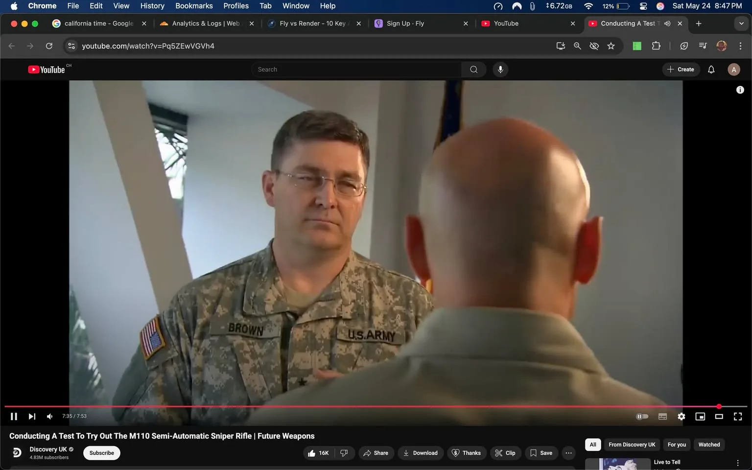 The image shows two individuals engaged in a conversation. 

1. **People**:
   - The person on the left is wearing a military uniform with a camouflage pattern. The uniform has a name tag that reads "BROWN" and an insignia indicating they are part of the U.S. Army. They have short, dark hair and are wearing glasses. Their expression appears serious and focused as they listen to the other person.
   - The person on the right has a bald head and is wearing a light-colored shirt. Their back is facing the camera, making it difficult to see their facial expression. 

2. **Setting**:
   - The background features a wall with a light-colored surface and a window that allows some natural light to enter. The window is partially obscured by a vertical structure, possibly a column or wall feature.
   - There is an American flag visible in the background, indicating a formal or official setting, likely related to military or governmental activities.

3. **Context**:
   - The scene appears to be part of a video segment, possibly an interview or demonstration related to military equipment, as indicated by the title of the video, "Conducting A Test To Try Out The M110 Semi-Automatic Sniper Rifle | Future Weapons."
   - The video is hosted on YouTube, as indicated by the interface at the bottom of the image, which includes options for viewing, subscribing, and interacting with the content.

4. **Text and Logos**:
   - The visible text includes the name "BROWN" on the uniform and the title of the video at the bottom of the screen. The YouTube logo is also present in the top left corner, along with other interface elements typical of the platform.

Overall, the image captures a moment of discussion or instruction in a military context, with a focus on the individuals and their attire, as well as the formal setting indicated by the presence of the American flag.