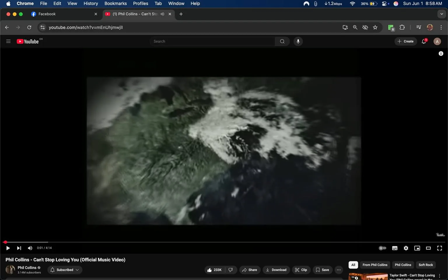 The image displays a screenshot from a YouTube video titled "Phil Collins - Can't Stop Loving You (Official Music Video)." The video is currently paused at the beginning, showing a visual that appears to be an aerial view of a landmass, possibly depicting a portion of Earth. The land is predominantly green, with some areas appearing white, likely representing clouds or snow. The edges of the image fade into a dark background, creating a contrast that emphasizes the land and clouds.

At the bottom of the screen, there is a video control bar showing the playtime at 0:01 out of a total of 4:14 minutes. The video has a view count of 233K, and the channel name "Phil Collins" is displayed, along with a subscriber count of 3.14 million. The interface includes buttons for sharing, downloading, and saving the video, as well as a clip option.

The top of the image features a web browser interface with tabs for Facebook and YouTube. The YouTube tab is highlighted, indicating that the user is currently viewing the video. The overall layout is typical of a desktop browser, with a dark theme for the YouTube interface.

No people, clothing, or facial expressions are visible in this image, as it focuses solely on the video content and the browser interface. The setting is digital, specifically within a web browser environment, and there are no additional environmental context indicators present.