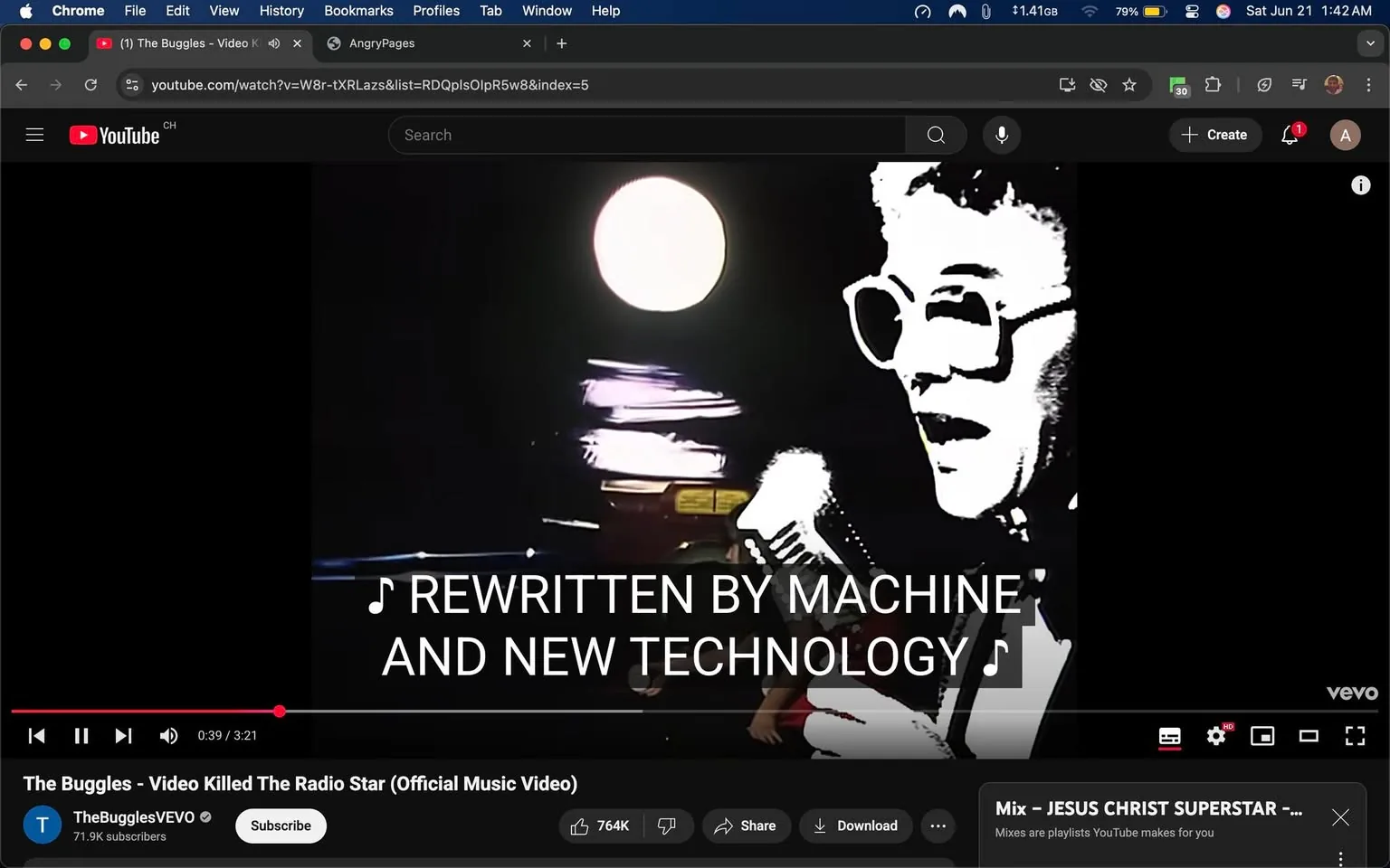 The image displays a still from a music video titled "Video Killed The Radio Star" by The Buggles. The video is playing on a YouTube interface, which is visible at the top of the image. The YouTube logo is present, along with the channel name "TheBugglesVEVO" and a subscriber count of 71.9K. Below the video, there are options to share, download, and subscribe.

In the foreground, a male figure is depicted, possibly a performer, holding a microphone. He is wearing large, round glasses and has a light-colored, possibly white or gray, hairstyle. His expression appears animated, suggesting he is singing or speaking. The background features a bright circular light source, which could be a spotlight, and there are blurred, colorful lights or objects that suggest a performance setting.

The text overlay in the center of the image reads, "REWRITTEN BY MACHINE AND NEW TECHNOLOGY," indicating a lyrical element from the song. The text is bold and white, contrasting against the darker background, making it easily readable.

The overall setting appears to be a stage or performance area, with a dark backdrop that enhances the visibility of the performer and the text. The image captures a moment from the music video, emphasizing the artistic and technological themes present in the song.