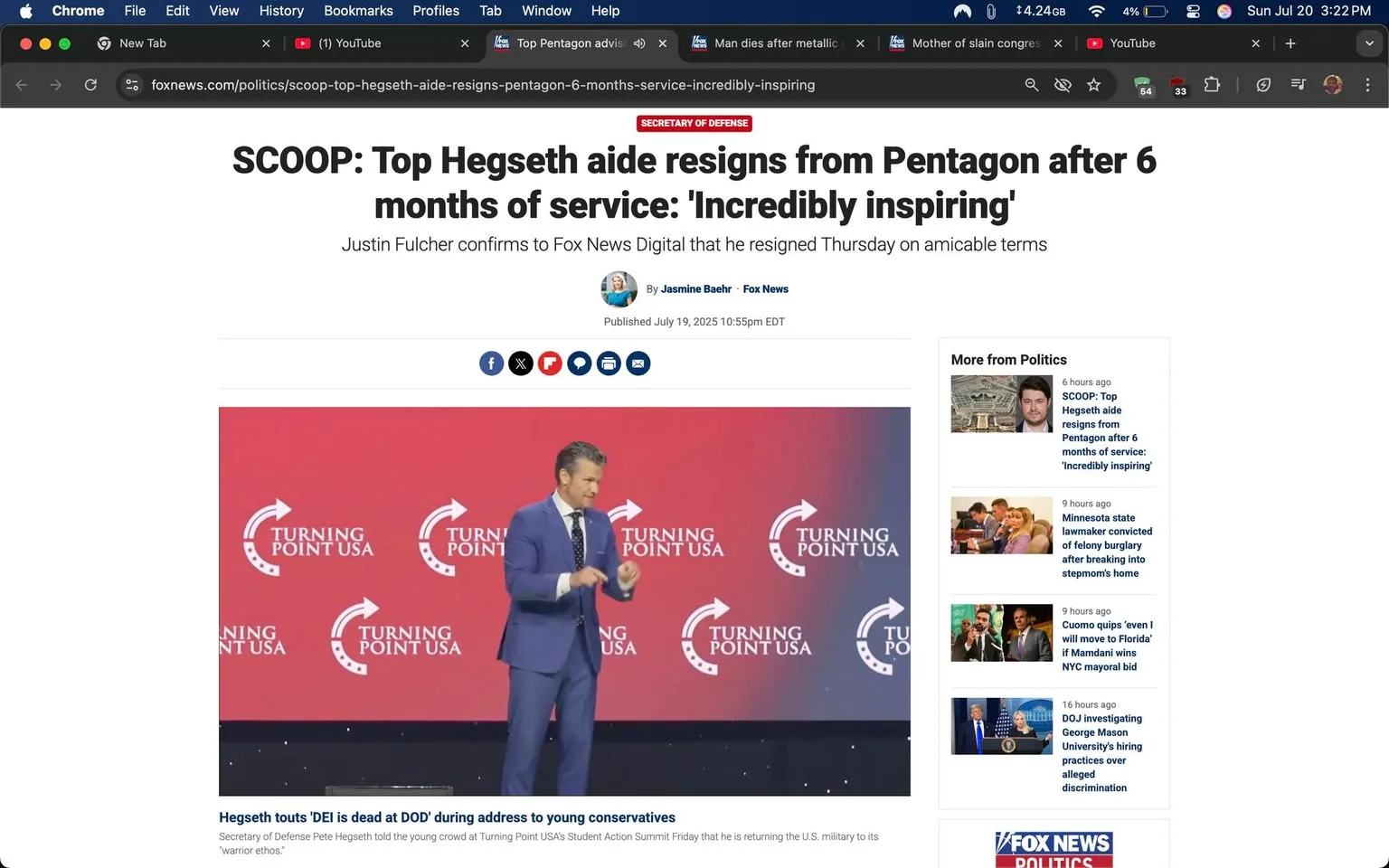 The image features a man on stage at an event, likely a conference or summit, with a backdrop displaying the "Turning Point USA" logo prominently. He is dressed in a tailored blue suit, white shirt, and a blue tie, suggesting a formal or professional setting. The man appears to be gesturing with his hands, possibly emphasizing a point during his speech. His expression seems engaged and animated, indicating enthusiasm or passion about the topic he is discussing.

The background is a vibrant red with the "Turning Point USA" logo repeated, creating a strong visual identity for the organization. The overall atmosphere appears energetic and focused, likely aimed at a young audience, as suggested by the context of the event.

The text above indicates that this is related to a resignation from a position at the Pentagon, which adds a layer of political significance to the scene. The tone of the event seems to be motivational, appealing to young conservatives.