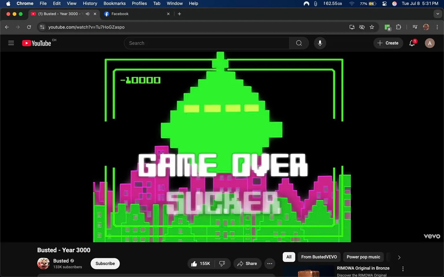 The image presents a vibrant, retro-style video game screen, reminiscent of classic arcade games. The background is predominantly black, which enhances the vivid colors of the graphics. Central to the image is a large, pixelated green spaceship, shaped like a classic UFO, with three horizontal lines on its underside, possibly representing lights. This spaceship is positioned above a stylized cityscape depicted in shades of pink and purple, with blocky, geometric buildings that evoke a sense of a futuristic or alien environment.

Prominently displayed across the center of the screen is the text "GAME OVER SUCKER," rendered in bold, white pixelated font. The phrase conveys a playful, taunting tone, typical of video game culture, suggesting a lighthearted defeat. The word "SUCKER" adds an element of cheekiness, reinforcing the playful nature of the game over message.

Above the spaceship, there is a score indicator showing "-10000," indicating a negative score, which further emphasizes the game's defeat. The overall composition is symmetrical, with the spaceship and text centrally aligned, drawing the viewer's eye immediately to the message of defeat.

The image is framed by neon green lines that create a border, enhancing the retro aesthetic and giving it a digital feel. The combination of colors—green, pink, and purple—contributes to a nostalgic vibe, reminiscent of 8-bit graphics from the 1980s and 1990s.

In the lower section of the image, there is a YouTube interface visible, indicating that this is a screenshot from a video titled "Busted - Year 3000." The channel name "Busted" is displayed alongside a verification checkmark, suggesting it is an official channel with a substantial following of 133K subscribers. Below the video, there are options to "Subscribe," "Like," and "Share," typical of YouTube's interactive features.

The overall mood of the image is playful and nostalgic, appealing to fans of retro gaming and pop culture. The use of bright colors and bold text creates an energetic atmosphere, while the "GAME OVER" message adds a humorous twist to the concept of losing in a game. The image effectively captures the essence of a fun, lighthearted gaming experience, inviting viewers to engage with the content.