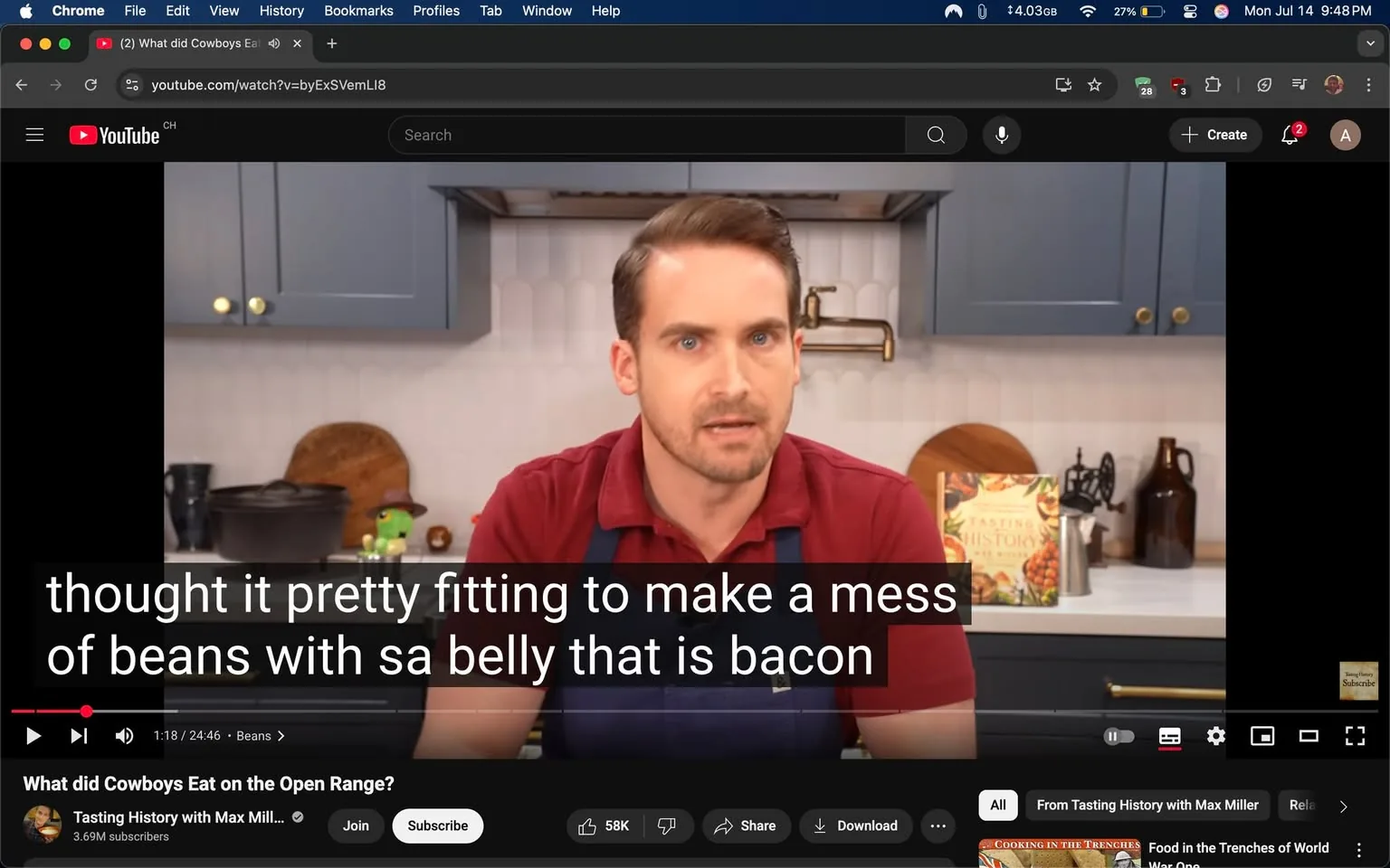 • subjects: man, kitchen items, cookbook  
• actions: man speaking, gesturing, explaining  
• context: YouTube interface, cooking show, blue cabinets, white tiles, wooden cutting board, pot, decorative items, text overlay  
• risks: none  
• mood: informative, casual, engaging