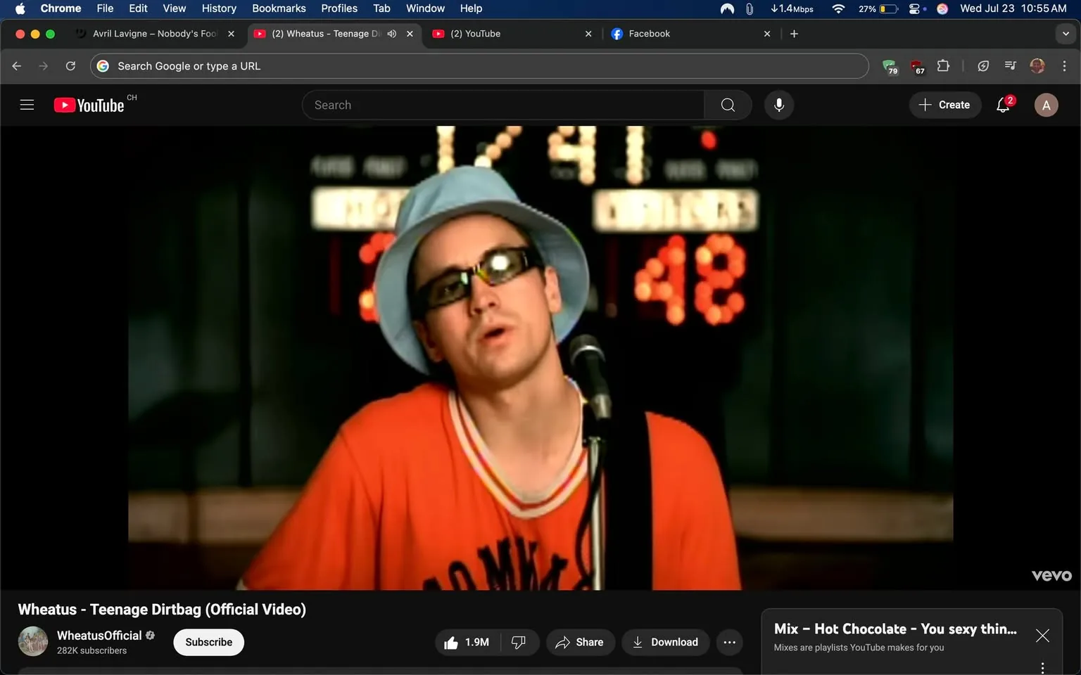 The image captures a scene from the music video for "Teenage Dirtbag" by Wheatus. The focus is on a male singer, who appears to be in a performance setting. He has a somewhat laid-back demeanor, wearing a bright orange shirt with a sporty vibe, featuring a white and red striped collar. His look is completed by a light blue bucket hat and dark sunglasses, giving him a casual, youthful appearance that aligns with the song's themes of teenage angst and unrequited love.

In the background, there are illuminated numbers that suggest a scoreboard, possibly indicating a sports event or a competition. The numbers displayed are "41" and "48," which adds to the atmosphere of a high school or youthful setting, resonating with the song's narrative about teenage experiences.

The singer's expression is one of introspection, as he seems to be lost in the moment, conveying a mix of nostalgia and longing. This emotional depth is a hallmark of the song, which tells a story of feeling out of place and yearning for someone who seems unattainable.

The overall tone of the image is vibrant yet reflective, encapsulating the essence of early 2000s pop culture, where themes of teenage life were often explored in music and media. The combination of the singer's attire, the setting, and the emotional expression creates a vivid snapshot of a moment that resonates with many who have experienced the trials of adolescence.

The branding is subtle, with the YouTube interface visible at the bottom, indicating that this is part of a larger collection of music videos. The channel name "WheatusOfficial" suggests that this is an official upload, adding a layer of authenticity to the viewing experience. The number of views and likes displayed indicates the song's popularity, reflecting its lasting impact since its release.

In summary, this image encapsulates a moment of youthful expression, blending music, emotion, and nostalgia in a way that resonates with many viewers, making it a memorable part of early 2000s music history.