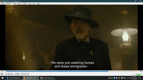Sheriff Jim Courtright, played by Billy Bob Thornton in the series "1883," is depicted in this frame. He stands indoors, wearing a dark suit and a wide-brimmed hat, which is typical of the period attire from the late 19th century depicted in the show. His expression is serious, with a hint of authority, fitting for his role as a sheriff. The lighting is dim and atmospheric, enhancing the historical ambiance of the scene.
In the background, a softly glowing lamp adds to the warm, sepia-toned environment. This setting suggests a saloon or similar establishment, common in the Western genre. The subtitles indicate a conversation about watering horses and immigrants, contributing to the narrative tension typical of the show's exploration of the American frontier experience.
- Title: "1883 S01E02"
- Site / app: "VLC media player"
- Captions / subtitles: "- We were just watering horses and these immigrants--"