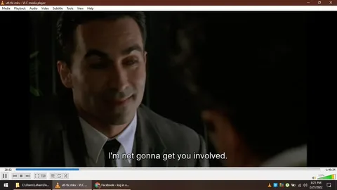 The image is a screenshot from a video being played on VLC media player, specifically a file named "utl-tlc.mkv". It shows a close-up of a man in a suit, engaging in a conversation with someone who is partially visible. The background is dark and the lighting is dim, suggesting an intimate or serious setting. The man's expression is subtle, possibly indicating a sense of reassurance or confidentiality as he says, "I'm not gonna get you involved," which is subtitled at the bottom of the screen. The interface of the VLC media player is visible, showing standard playback controls and the timestamp 28:52 of a total duration of 1:49:34. The taskbar at the bottom displays the date and time as 8:21 PM on 2/27/2022.