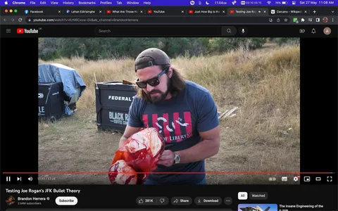 This video frame from YouTube features Brandon Herrera outdoors, engaging in an experiment related to testing Joe Rogan's JFK bullet theory. Herrera, wearing a navy blue t-shirt with a graphic of the Statue of Liberty and text, stands in a grassy area holding a large, bloodied object, likely part of the experiment setup. He is dressed casually, sporting sunglasses and a cap, indicating a relaxed yet focused demeanor. The scene is set during the day, with ample natural light illuminating the surroundings.
In the background, there are two large black containers, one labeled "BLACK RIFLE COFFEE COM" and the other "FEDERAL," suggesting sponsorship or thematic elements related to firearms or ballistics. The setting is rustic and grassy, fitting for an outdoor shooting or testing range. The video’s title, "Testing Joe Rogan’s JFK Bullet Theory," implies that the content explores historical or forensic analysis through practical demonstration. The atmosphere is investigative and practical, aimed at a curious audience interested in experimental verification of popular theories.
- Title: "Testing Joe Rogan’s JFK Bullet Theory"
- Channel / profile: "Brandon Herrera"
- Site / app: "YouTube"