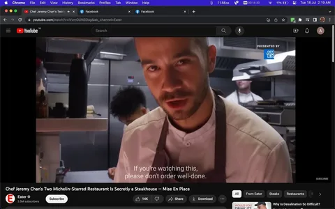 Chef Jeremy Chan is featured prominently in this YouTube video frame, captured inside a professional kitchen. The atmosphere is bustling, with multiple chefs visibly engaged in culinary tasks. Jeremy Chan, wearing a white chef's jacket and a brown apron, is positioned in the foreground. He leans slightly forward and addresses the camera directly with a focused expression. The lighting is bright, emphasizing the stainless steel surfaces and the organized chaos typical of a high-end kitchen. Behind him, other chefs are busy, adding to the dynamic energy. The setting is professional and efficient, underscoring the high standards of a Michelin-starred establishment. Prominent on-screen text humorously advises viewers, “If you're watching this, please don't order well-done,” highlighting a common culinary preference for steak preparation. The video is presented by Eater, a channel known for its culinary content, and is sponsored by American Express, as indicated by the logo in the upper right corner.
