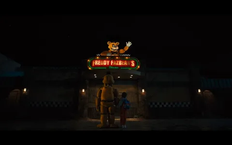 The image depicts a nighttime scene outside a building with a bright, colorful sign that reads "FREDDY FAZBEAR'S." Above the sign is a cartoonish bear mascot waving, which is consistent with the theme of the "Five Nights at Freddy's" franchise, known for its horror elements featuring animatronic characters.
In the foreground, an animatronic character, resembling a bear, stands next to a person. The animatronic is large, with a yellowish-brown color, and wears a black bowtie and top hat. The person beside it appears to be a young individual, wearing a blue jacket and red pants, with a backpack. They stand together facing the entrance, implying a moment of anticipation or curiosity.
The building's exterior is somewhat worn, with brick walls and checkerboard patterns, casting an eerie yet nostalgic ambiance. The lighting is dim, with only the sign and a few exterior lights illuminating the scene, enhancing the mysterious and suspenseful atmosphere typical of the "Five Nights at Freddy's" series.