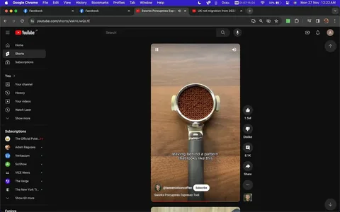The screenshot captures a YouTube Shorts video featuring a coffee preparation scene. At the center is a portafilter filled with finely ground coffee placed on a wooden surface, demonstrating the use of the "Sworks Porcupress Espresso Tool." The tool is implied to create a pattern on the coffee grounds, as mentioned in the subtitle "leaving behind a pattern that looks like this." The video's channel, "@tannercolsoncoffee," is highlighted, suggesting a focus on coffee-related content. The interface shows typical YouTube elements, including like and dislike buttons, view count, and options to share or comment. The dark mode interface of YouTube adds contrast to the vibrant coffee grounds and stainless steel of the portafilter, enhancing the visual appeal. The scene is likely set in a kitchen environment, indicated by the wooden background. The overall atmosphere is educational and aimed at coffee enthusiasts looking to improve their espresso-making skills.
- Channel / profile: "@tannercolsoncoffee"
- Site / app: "YouTube"
- Captions / subtitles: "leaving behind a pattern that looks like this"