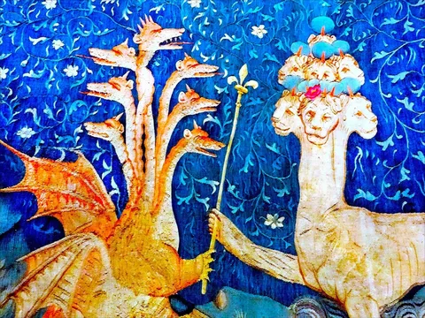This vibrant medieval illustration features an intricate depiction of fantastical creatures set against a richly detailed blue background. On the left, a multi-headed dragon with orange tones is depicted, each head uniquely crafted, capturing a sense of mythical ferocity. The dragon's wings are spread, showcasing detailed scales and a fiery hue that contrasts with the cool blue backdrop. On the right, another mythical beast with multiple heads is portrayed. This creature is adorned with a crown on each head, adding a regal and mysterious aura to its appearance. The creatures are engaged, each holding a staff, symbolizing a connection or conflict. The background is filled with swirling floral patterns, enhancing the tapestry's intricate design. The use of vivid colors and detailed patterns reflects the traditional style of medieval art, creating a scene that is both captivating and enigmatic.