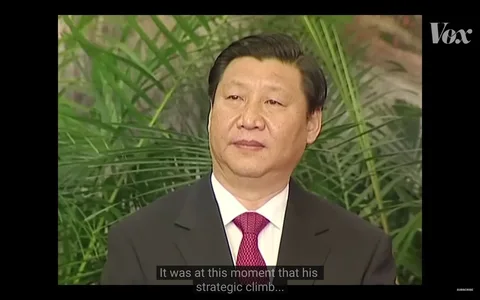 Xi Jinping is depicted in this video frame from a Vox YouTube channel segment. He is dressed in a formal black suit, white shirt, and a red tie, suggesting the setting is a significant event or meeting. The background features lush green plants, adding a natural contrast to the formality of his attire. Xi Jinping's expression is calm and composed, fitting for a public appearance. The lighting is soft, highlighting his face and creating a professional ambiance. The video appears to be part of a discussion or analysis, indicated by the subtitle at the bottom, stating, "It was at this moment that his strategic climb..." This suggests the focus is on Xi Jinping's political journey or leadership strategy. The overall composition directs attention to his presence and demeanor, emphasizing his role and influence.
- Title: "..."
- Channel / profile: "Vox"
- Site / app: "YouTube"
- Captions / subtitles: "It was at this moment that his strategic climb..."