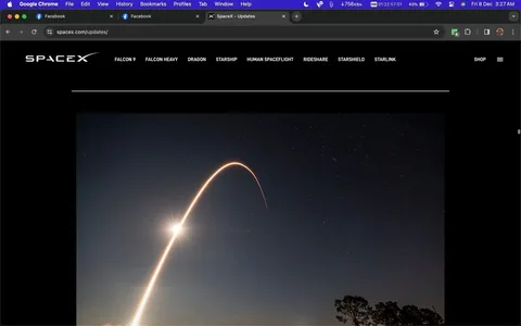 The image is a screenshot of a webpage from the SpaceX website, specifically the "Updates" section. The SpaceX logo is prominently displayed in the upper left corner, with a navigation bar listing different topics such as "Falcon 9," "Falcon Heavy," "Dragon," "Starship," "Human Spaceflight," "Rideshare," "Starshield," and "Starlink." The central image captures the dramatic arc of a rocket launch, likely a Falcon 9, against a clear night sky dotted with stars. The long exposure photograph beautifully traces the trajectory of the rocket as it ascends, creating a bright, curved line that stands out against the dark sky. In the lower right, a silhouette of trees adds depth and context to the scene. The overall mood is one of awe and inspiration, highlighting the grandeur of space exploration. The website's dark theme complements the nighttime setting, drawing focus to the luminous rocket trail.