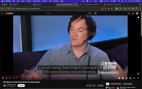 Quentin Tarantino is featured in an interview setting, likely a radio show, as indicated by the visible "Howard Stern" and "SiriusXM Satellite Radio" logos. He wears a blue, short-sleeve, button-up shirt and large headphones, suggesting he's actively engaged in a discussion. The lighting is soft, and the background is a gradient of blues, contributing to a professional and focused atmosphere. Tarantino appears to be gesturing with his hands, emphasizing a point while speaking. The video frame includes subtitles, with the current line discussing financial aspects related to "Pulp Fiction" and "Kill Bill," mentioning Disney's ownership of Miramax. The YouTube video is titled "Everything You Didn't Know About The Hateful Eight" and is from the channel "Kolo Kino clips," indicating a focus on lesser-known insights about Tarantino's films. The setting is likely within a studio, characterized by sleek, modern furnishings and equipment typical of a professional radio broadcast environment.