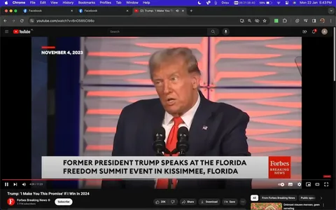 The image is a screenshot from a YouTube video titled "Trump: 'I Make You This Promise' If I Win In 2024," uploaded by the channel Forbes Breaking News. It captures a moment during a speech by Trump at the Florida Freedom Summit event in Kissimmee, Florida. Trump is visible in the foreground, standing behind a podium with microphones. He is dressed in a dark suit, white shirt, and red tie, and appears to be speaking with a serious expression.
The background features a patterned wall with horizontal lines in alternating colors, creating a dynamic and somewhat formal setting. The lighting is bright and professional, typical of an indoor event setup. The on-screen text provides context for the event, emphasizing the location and nature of the speech. The branding of Forbes Breaking News is visible in the lower right corner, indicating the source of the video.