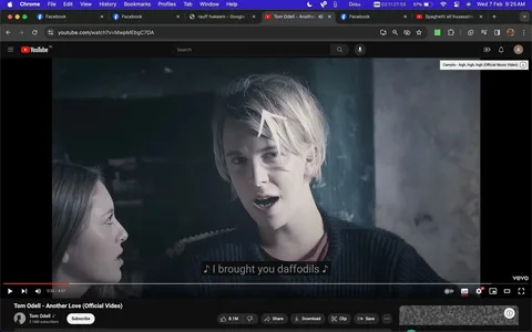 This image is a video frame from the official music video for "Another Love" by Tom Odell, visible on YouTube. The title and Odell's channel name are clearly displayed, indicating this is an official release. The video features Tom Odell, who is in the foreground, singing. His expression is earnest and engaged, complementing the moody ambiance of the scene. He is wearing a dark sweater and has light-colored hair, which stands out against the muted, dimly lit background. A female character is partially visible, looking towards him, adding a narrative element to the frame. The setting appears to be indoors, with a rustic, possibly aged, backdrop that enhances the emotional tone of the song. Subtitles at the bottom display the lyrics "I brought you daffodils," capturing a romantic theme. The overall color palette is subdued, focusing on blues and grays, which aligns with the melancholic mood of the song.
- Title: "Tom Odell - Another Love (Official Video)"
- Channel / profile: "Tom Odell"
- Site / app: "YouTube"
- Captions / subtitles: "I brought you daffodils"