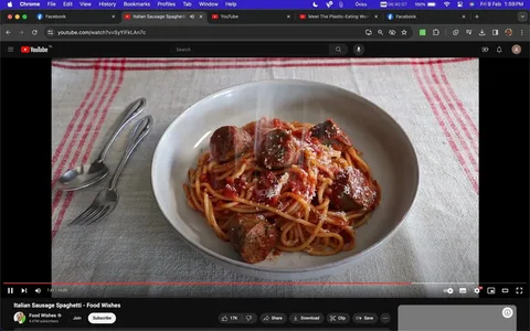 The screenshot is of a YouTube video titled "Italian Sausage Spaghetti - Food Wishes." It features a bowl of spaghetti with Italian sausage pieces mixed in, topped with a tomato-based sauce and sprinkled with cheese. The dish is placed on a white plate with a simple, homey backdrop of a table covered with a linen tablecloth featuring red stripes. The lighting is natural, highlighting the texture and color of the pasta and sauce, making the food appear appetizing and fresh. To the left of the bowl, a fork and spoon rest on the table, suggesting a ready-to-eat setting. The YouTube interface is visible, with controls and video information such as views and likes at the bottom of the frame. This setting conveys a cozy, inviting atmosphere typical of a home-cooked meal presentation.
- Title: "Italian Sausage Spaghetti - Food Wishes"
- Channel / profile: "Food Wishes"
- Site / app: "YouTube"