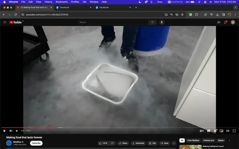 The screenshot displays a scene from a YouTube video titled "Making food that lasts forever" by the channel NileBlue. The scene takes place indoors, likely in a laboratory setting, judging by the concrete floor and equipment visible. In the foreground, there is a plastic container on the floor with smoke or vapor emanating from it, suggesting the use of a substance like liquid nitrogen. The vapor creates a foggy effect around the area. A pair of legs wearing jeans and black sneakers are visible near the container, indicating a person involved in the experiment, though their upper body is not visible.
The YouTube interface is visible at the top, displaying the title of the video and NileBlue's channel, which has 1.98 million subscribers. The video has a like count of 151K, and there are options for sharing, downloading, and saving the video. The scene is paused at 6:49 of a 28:48-long video. The browser's address bar shows the video URL, and additional browser tabs for Facebook are open. The overall mood is scientific and exploratory, with a focus on a potentially fascinating experiment related to food preservation techniques.