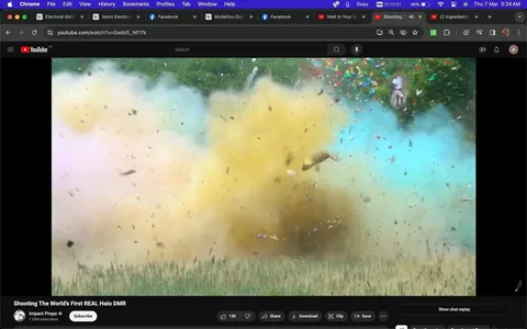 The image is a YouTube screenshot featuring a video titled "Shooting The World’s First REAL Halo DMR" from the channel Impact Props. The screenshot captures a dynamic outdoor scene with a large explosion, creating a colorful burst of smoke in various hues, including yellow, blue, and pink. Debris is visibly scattered across the frame, highlighting the intensity of the explosion. The grass in the foreground indicates a natural setting, and the treeline in the background provides a lush, green contrast to the vibrant colors of the smoke. The video likely involves a practical demonstration or experiment related to the Halo franchise, as suggested by the title. The YouTube interface is visible, showing elements like the like and share buttons, and the video’s view count and channel subscription information are prominently displayed. The overall mood is one of excitement and spectacle, characteristic of a high-energy demonstration or action sequence.