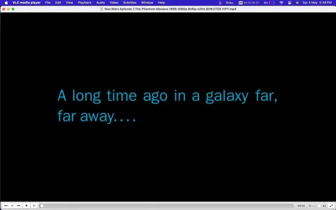 The image is a screenshot from the VLC media player showing the iconic opening text of "Star Wars." The background is black, with bright blue text in the foreground that reads, "A long time ago in a galaxy far, far away...." This text is well-known for its association with the Star Wars film franchise, setting the stage for the epic space saga. The file name at the top of the VLC window indicates that this is from "Star.Wars.Episode.1.The.Phantom.Menace.1999.1080p.BrRip.x264.BOKUTOX.YIFY.mp4," suggesting it is the beginning of "Star Wars: Episode I – The Phantom Menace." The player interface shows standard controls, with a progress bar at the bottom. The timestamp indicates the video is 25 seconds in, which is typically the timing for this introductory sequence. The style is minimalistic, focusing solely on the text to evoke anticipation and nostalgia for the Star Wars universe.