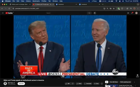 The image is a screenshot from a YouTube video titled "Biden and Trump speak on institutional racism in America," published by ABC News. The screenshot captures a split-screen view of a presidential debate between Trump and Biden. Both are standing at podiums with microphones, engaged in a discussion. Trump is on the left, wearing a dark suit, white shirt, and a red tie, gesturing with his hands. Biden is on the right, wearing a dark suit, white shirt, and a blue tie, with a slightly smiling expression. The background is a consistent blue with faint text, typical of a debate setting. The on-screen text includes "RACE IN AMERICA" and "PRESIDENTIAL DEBATE," indicating the topic of discussion. The video appears on the ABC News YouTube channel, with visible engagement statistics such as likes and subscriber count. The lighting is bright and even, emphasizing the formal setting of the debate.