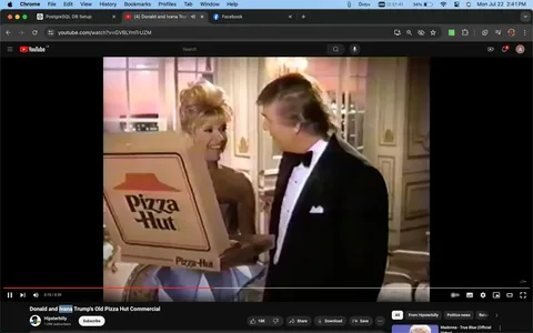In this video frame, Donald Trump is featured in a commercial setting. He is dressed in a formal black tuxedo with a white shirt, indicative of an elegant event or occasion. Next to him, a woman is holding a large Pizza Hut box, suggesting the scene is from an advertisement. The setting appears to be indoors, possibly a lavish room with ornate decor, adding to the formal and upscale ambiance. The lighting is warm, enhancing the luxurious atmosphere. Both individuals are engaged in conversation, smiling, which adds a friendly and lighthearted mood to the commercial. The Pizza Hut logo is prominently displayed on the box in the woman's hands, emphasizing the brand being advertised. The frame is from a YouTube video titled "Donald and Ivana Trump's Old Pizza Hut Commercial," uploaded by the channel "Hipsterbilly." This suggests the video is nostalgic, revisiting a past advertisement featuring Donald Trump.