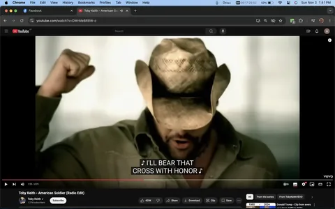 Toby Keith is depicted in a scene from his music video "American Soldier (Radio Edit)" on YouTube. Wearing a broad-brimmed cowboy hat and a casual, olive-green shirt, Toby Keith's posture is assertive, as he raises a fist in a gesture of strength and determination. His head is slightly bowed, adding a solemn, reflective mood to the scene. The lighting is soft and diffuse, giving the image a warm and somewhat nostalgic ambiance. The earthy tones of his attire complement the subdued background, which is out of focus, drawing attention to his expressive gesture and the emotion conveyed in the shot. The video frame captures a moment where the caption reads, "♪ I'LL BEAR THAT CROSS WITH HONOR ♪," matching the themes of patriotism and duty often present in Toby Keith's music. This scene is part of a larger narrative celebrating the resilience and dedication of soldiers, captured in the song's lyrics and visuals.
- Title: "Toby Keith - American Soldier (Radio Edit)"
- Channel / profile: "Toby Keith"
- Site / app: "YouTube"
- Captions / subtitles: "♪ I'LL BEAR THAT CROSS WITH HONOR ♪"