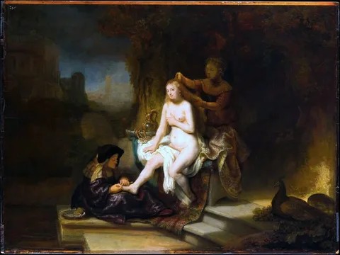 In the artwork, a nude female figure is seated on a stone platform, her body partially draped with a colorful fabric. She appears to be receiving attention from two other figures: one is a woman who is grooming her hair, while the other, positioned at her feet, is holding her foot. The setting is richly detailed, with a dark, atmospheric background that suggests an outdoor environment, possibly a garden or a secluded area. The figures are illuminated by soft light, enhancing the intimate nature of the scene. The overall composition conveys a sense of tenderness and care, with the presence of a peacock in the foreground adding to the opulence of the setting.