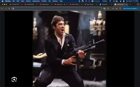 The image depicts a male figure in a dramatic pose, holding a firearm. He appears to be in a stylized, cinematic setting, likely from a film. 

**Clothing and Appearance:**
- The individual is dressed in a black pinstripe suit, which is tailored and fitted. 
- He has a white dress shirt underneath, with the collar slightly open and a hint of a white undershirt visible.
- The suit jacket has a pocket square, which is red, adding a pop of color to the outfit.
- His hair is dark and styled in a slicked-back manner, with a slightly tousled look.
- The expression on his face is intense, with his mouth open as if shouting or expressing strong emotion. His eyes are wide, conveying a sense of urgency or aggression.

**Action:**
- He is positioned in a dynamic stance, with his legs spread apart and knees slightly bent, suggesting movement or readiness.
- The firearm he is holding is a black assault rifle, with a prominent barrel and a tactical design. He grips it firmly with both hands, indicating he is prepared for action.

**Setting:**
- The background is dimly lit, with a luxurious, opulent feel. There are ornate chandeliers visible, suggesting a grand interior space, possibly a mansion or a lavish room.
- The floor appears to be carpeted, and there are hints of furniture in the background, though details are obscured by the lighting.

**Overall Context:**
- The image conveys a sense of high tension and drama, typical of action or crime genres in film. The character's pose and expression suggest a pivotal moment, possibly in a confrontation or climactic scene.

No readable text, logos, or trademarks are present in the image. The focus remains on the character and his immediate environment.